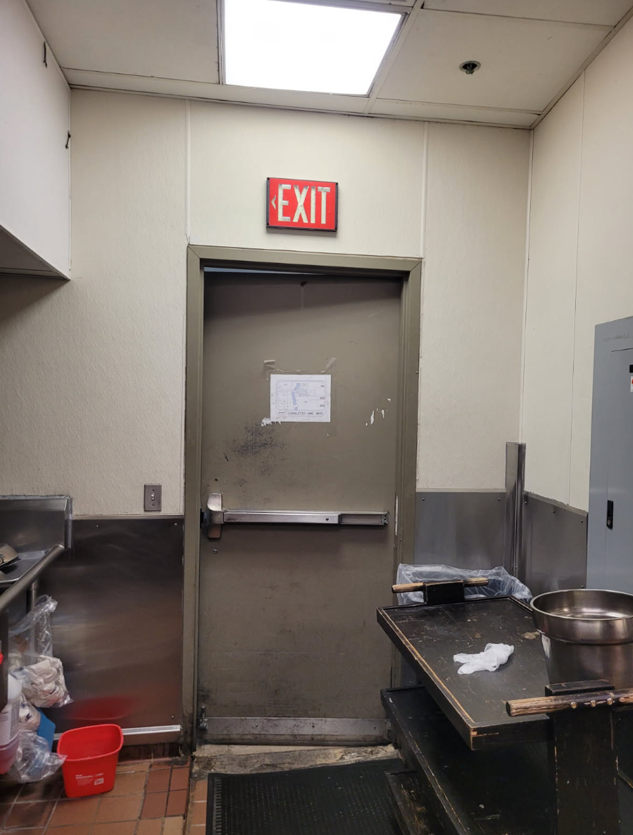 A kitchen with a red exit sign above the door