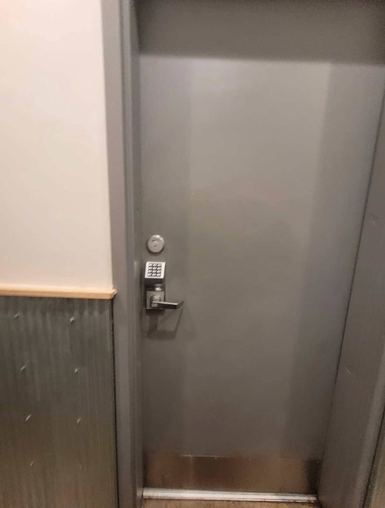 A door with a lock on it is in a hallway.