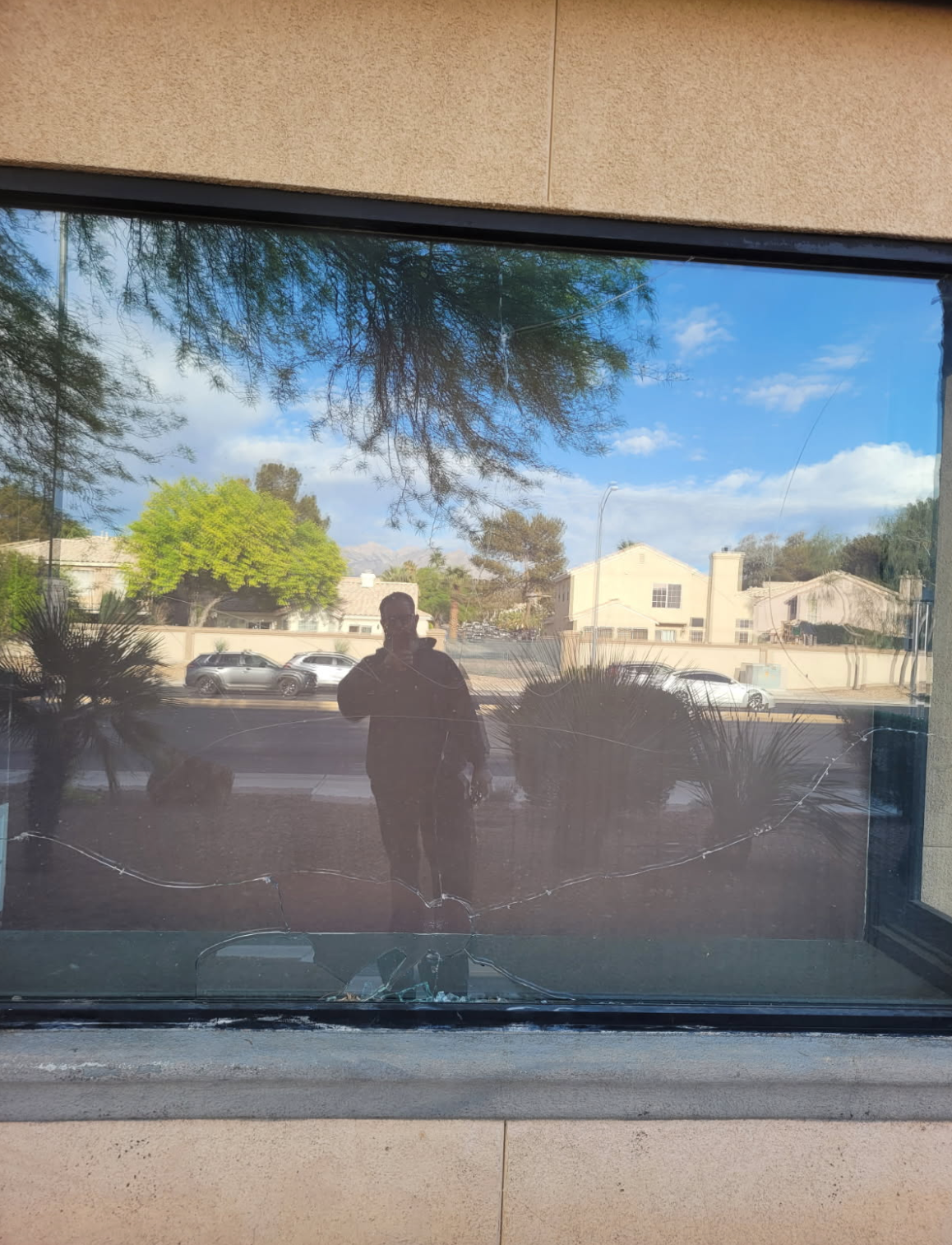 A man is standing in front of a window with his reflection in it.