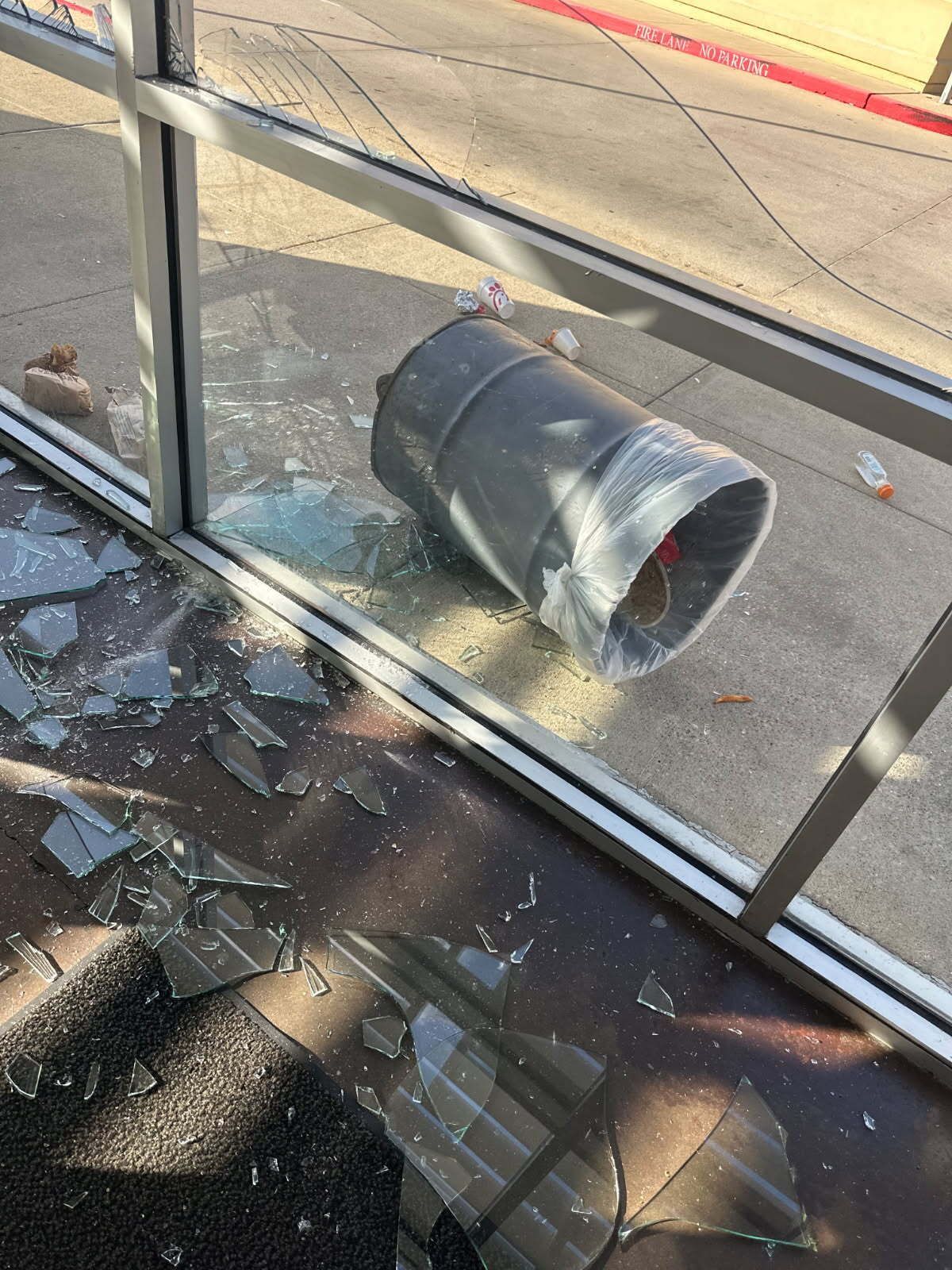 A broken glass window with a pipe coming out of it.