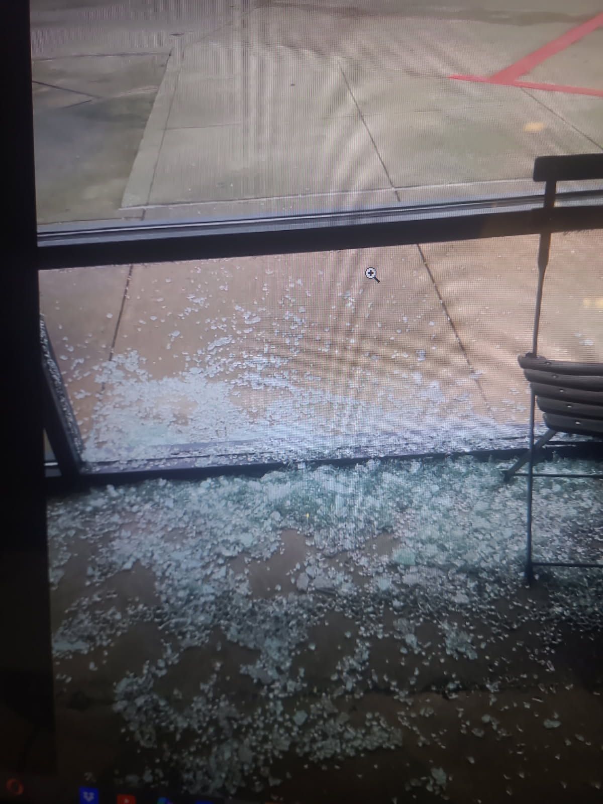 A broken glass window with a chair in front of it.