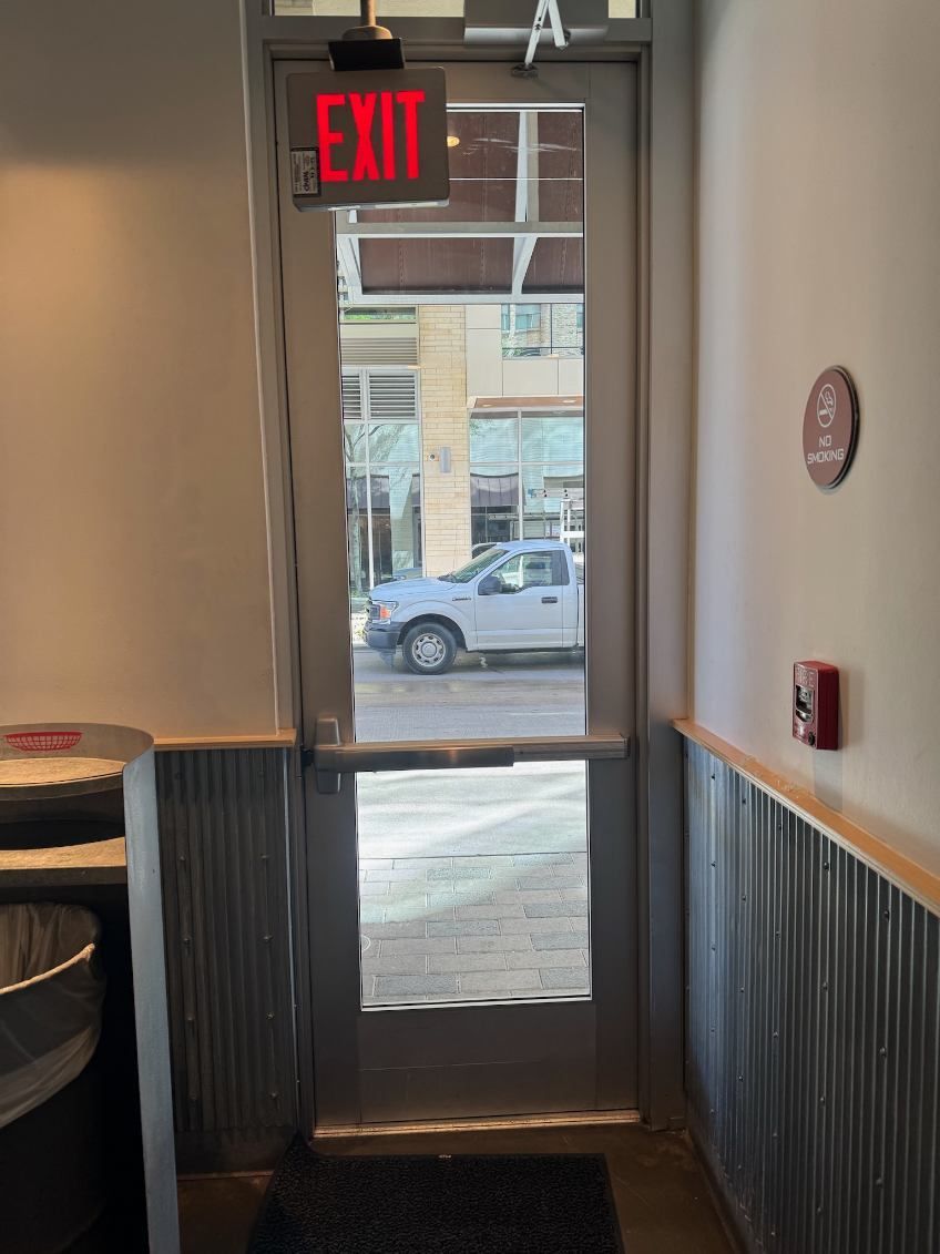 A red exit sign is above a glass door