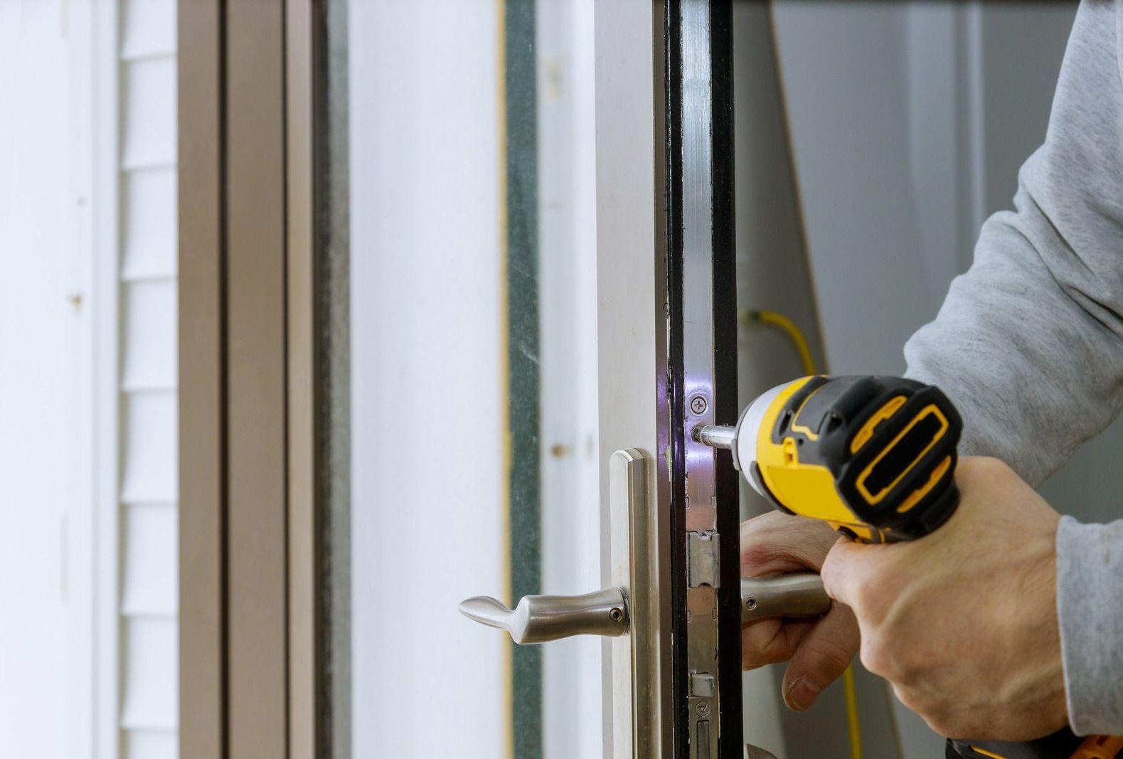 A man is fixing a door with a drill.