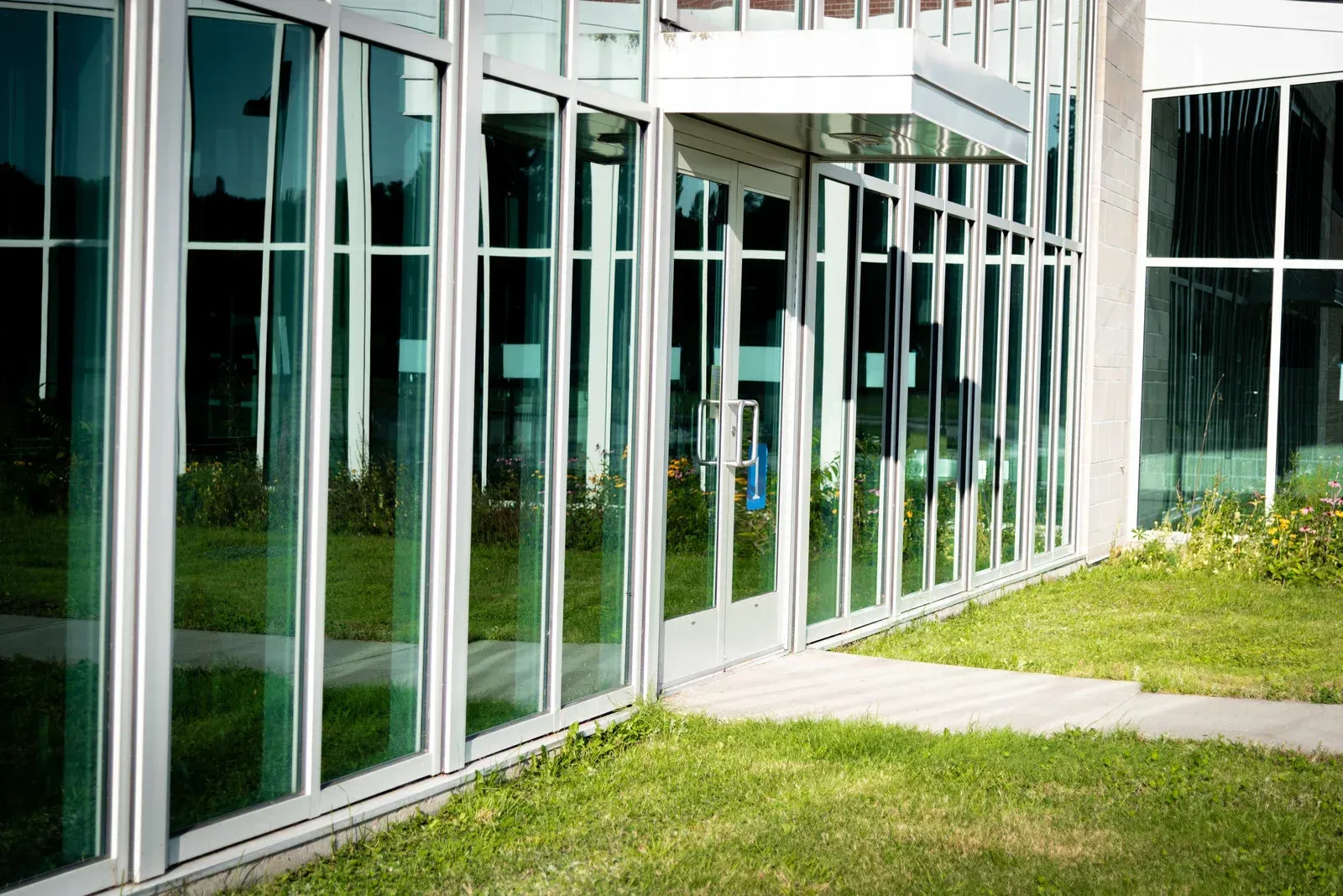 A large building with a lot of windows and a grassy area in front of it.