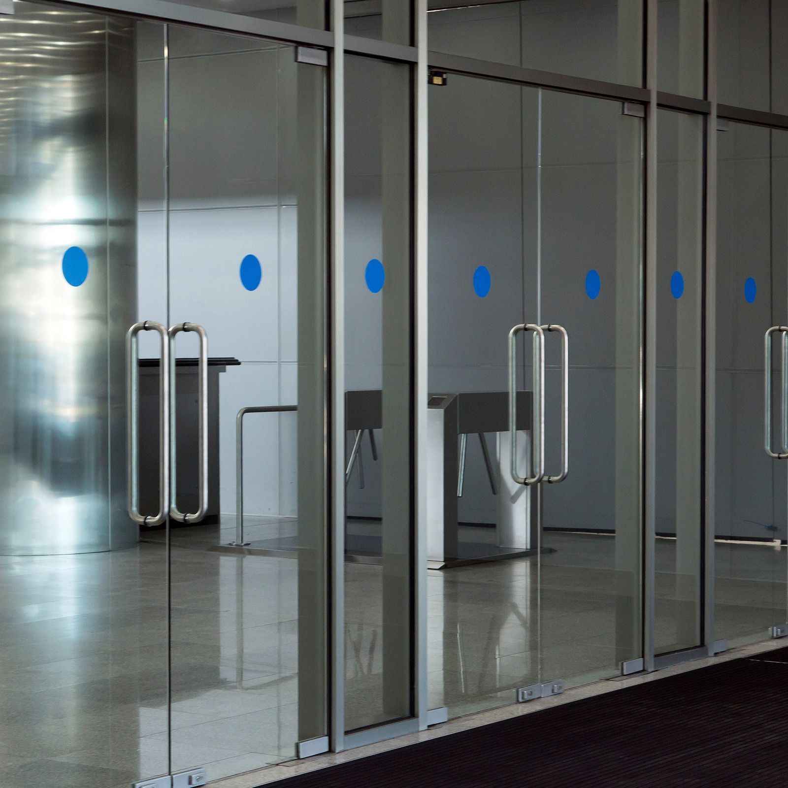 Glass doors with blue dots, silver handles, and a gray interior with furniture.