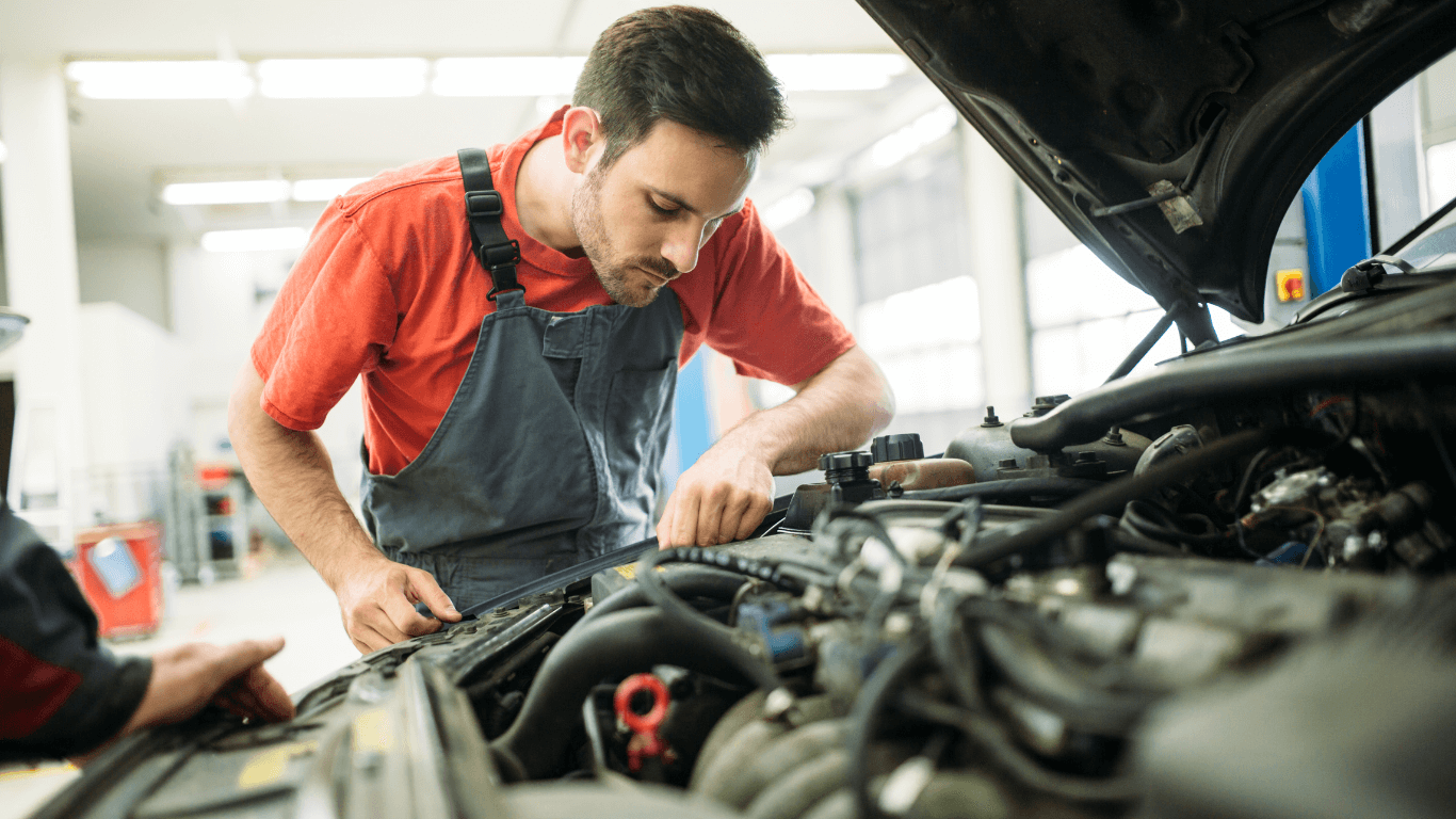 A mechanic looking under the hood of a car