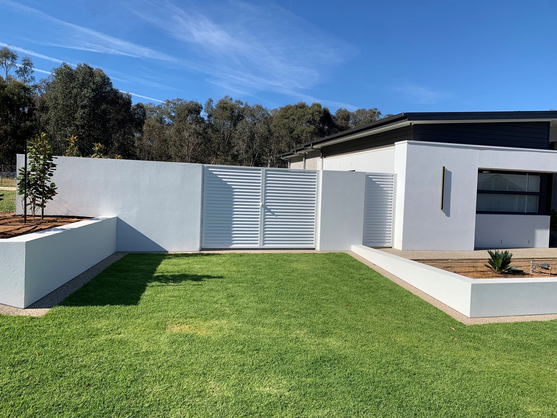 A white fence with a gate in front of a house.