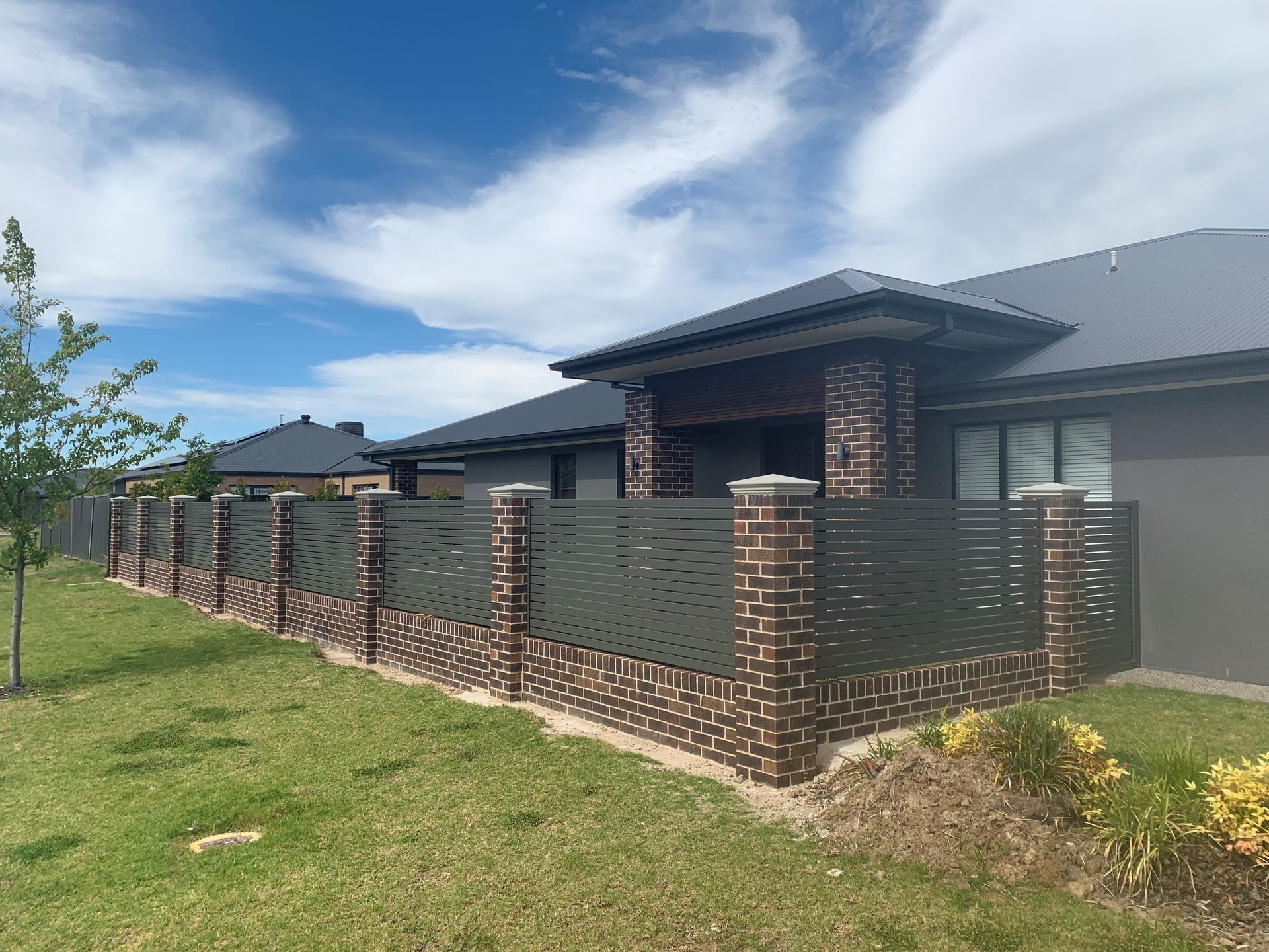 A black and white fence along a sidewalk in front of a house