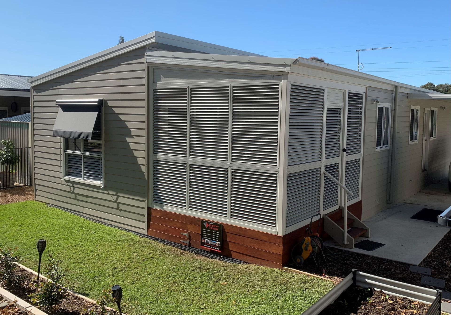 A bedroom with a bed , dresser , and shutters on the windows.