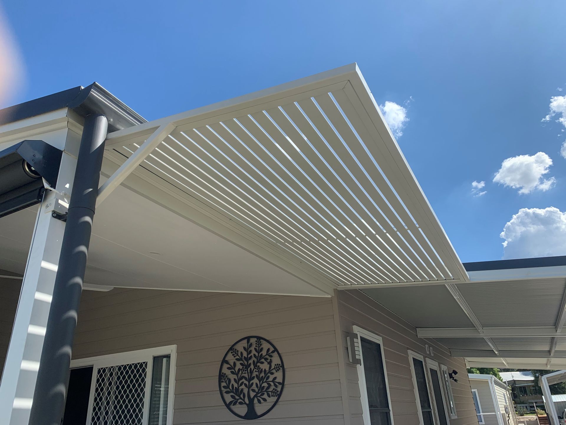 A white house with a black pergola on the front of it