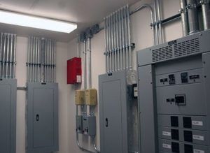 A room with a lot of electrical panels and boxes on the wall.