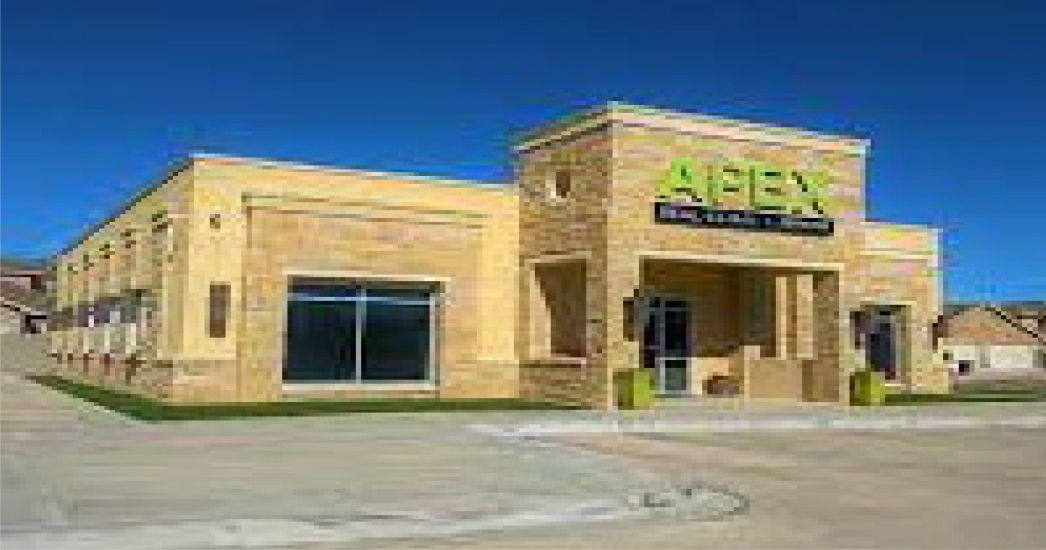 A large yellow building with a green sign that says apex on it.