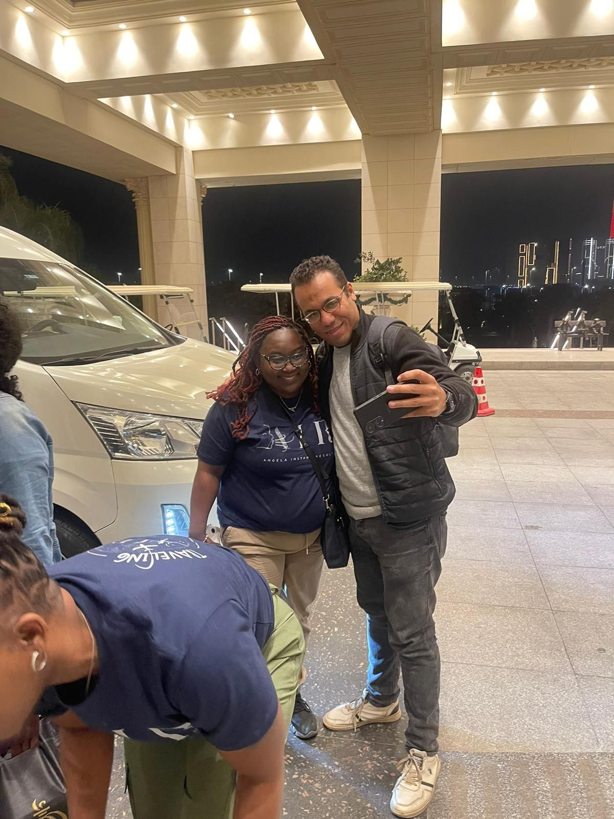 A man is taking a selfie with a woman in front of a car.