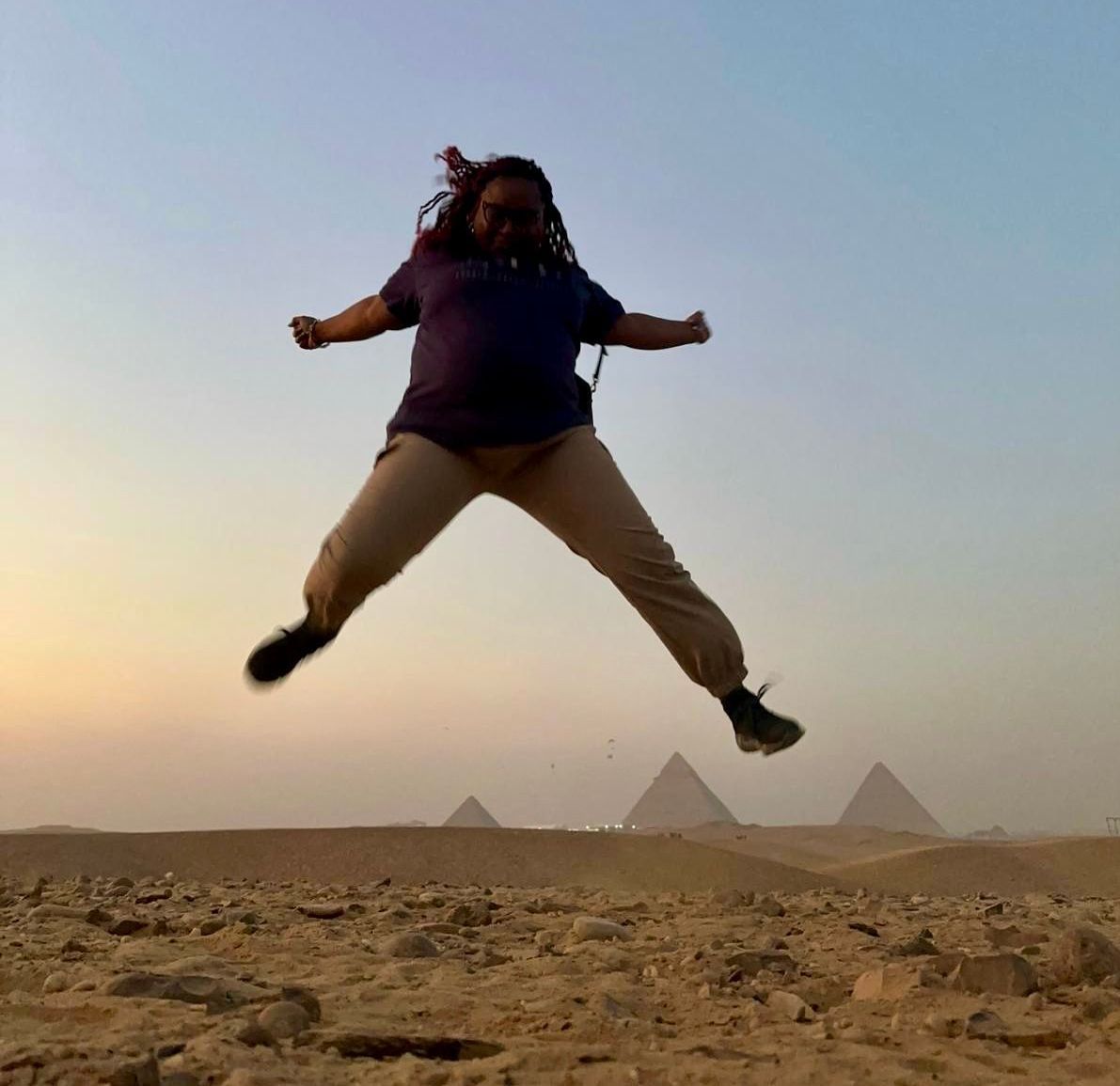 A woman in a purple shirt is jumping in the air