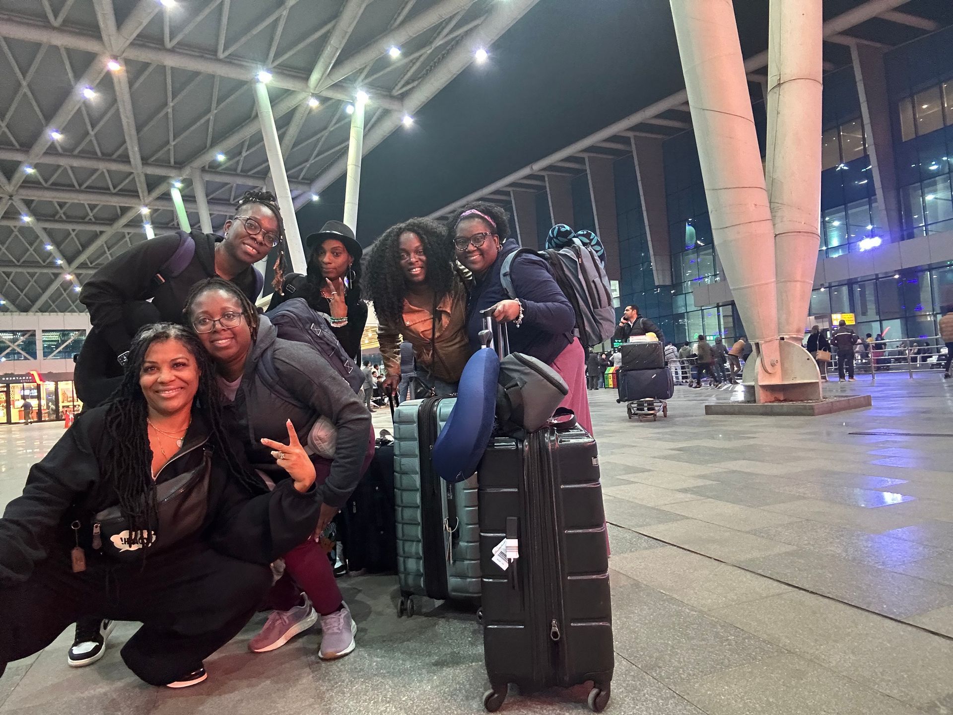 A group of women are posing for a picture with their luggage at an airport.