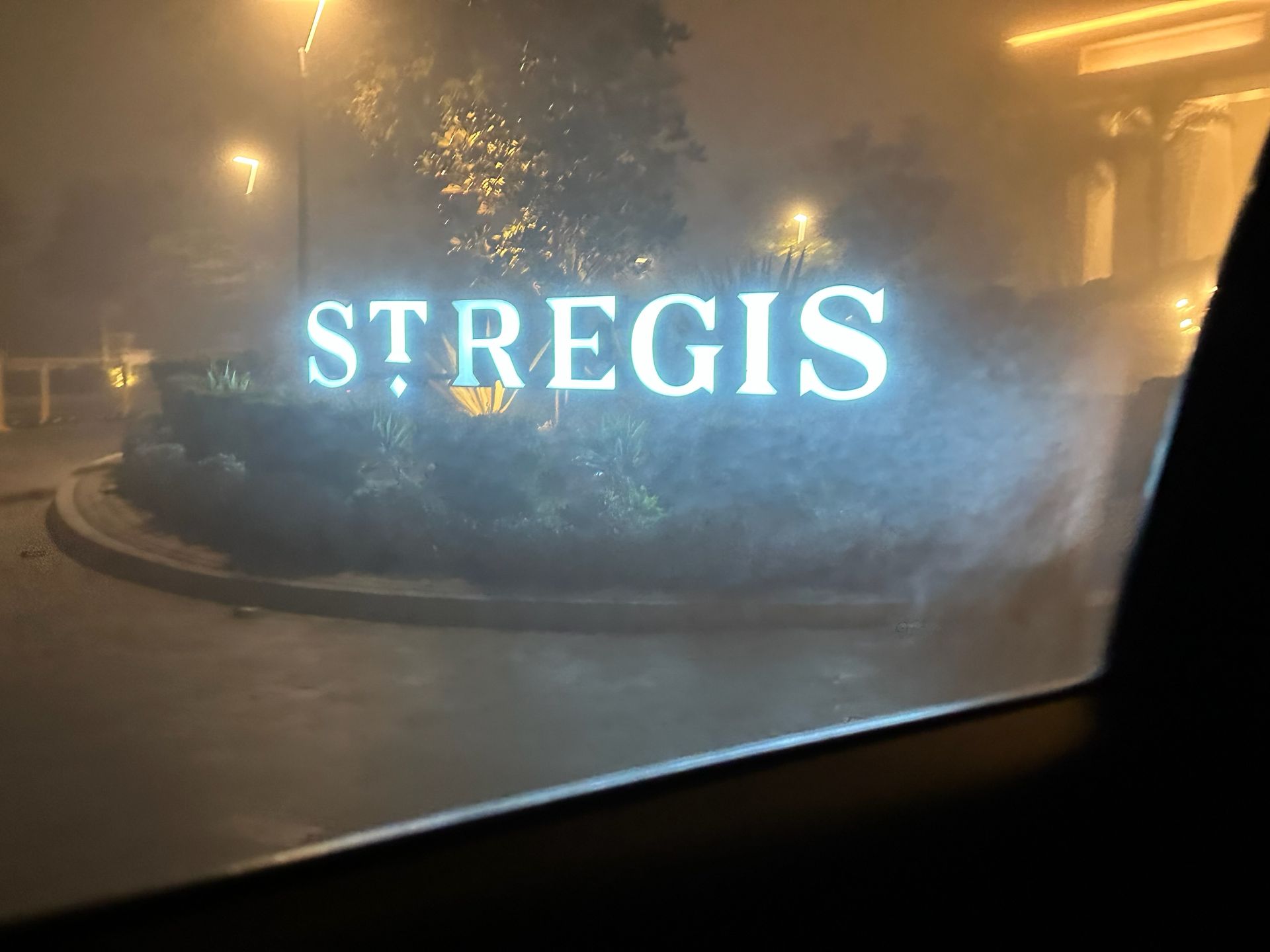 A sign that says st regis is lit up in the fog