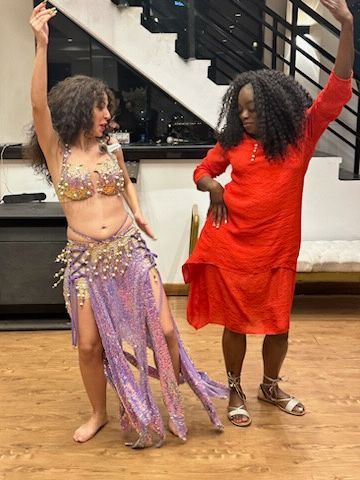 A woman in a red dress is dancing next to a woman in a purple dress.