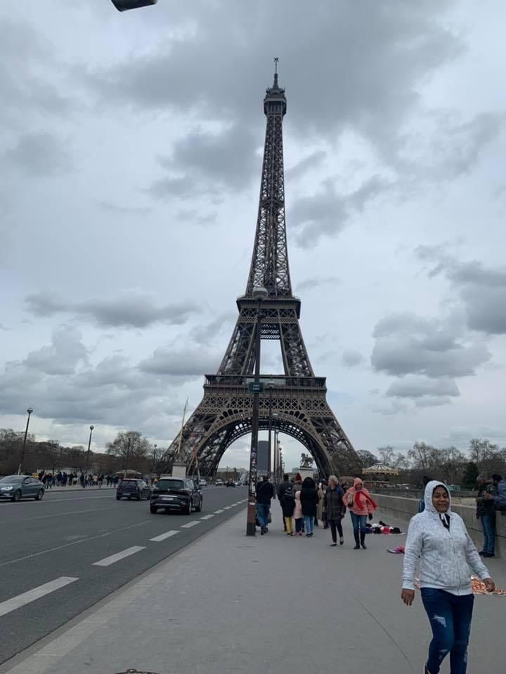 A woman is walking down a sidewalk in front of the eiffel tower