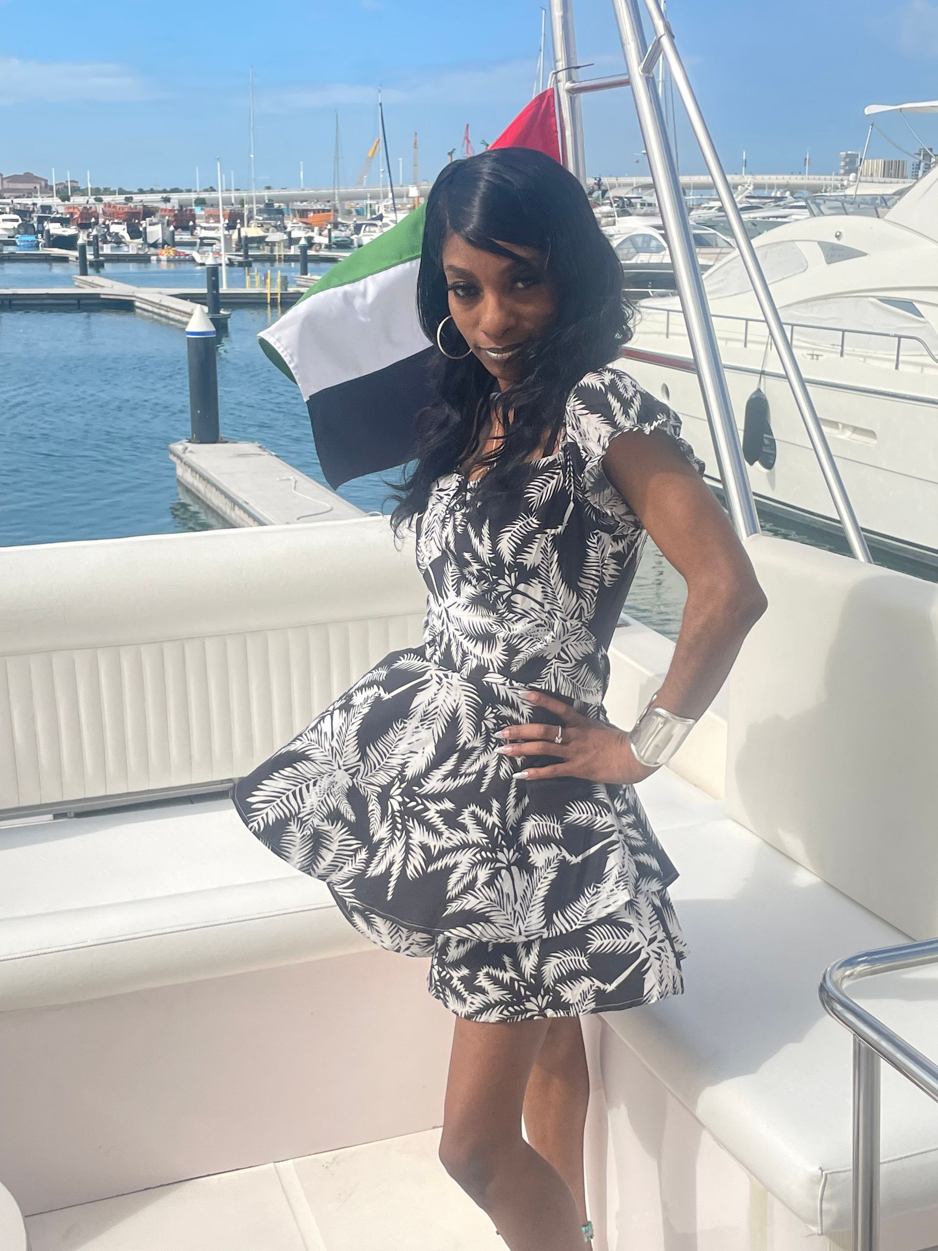 A woman in a black and white dress is standing on a boat