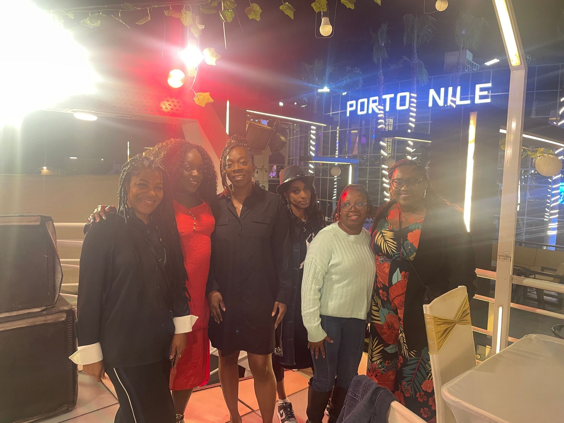 A group of women are posing for a picture in front of a sign that says porto nile.