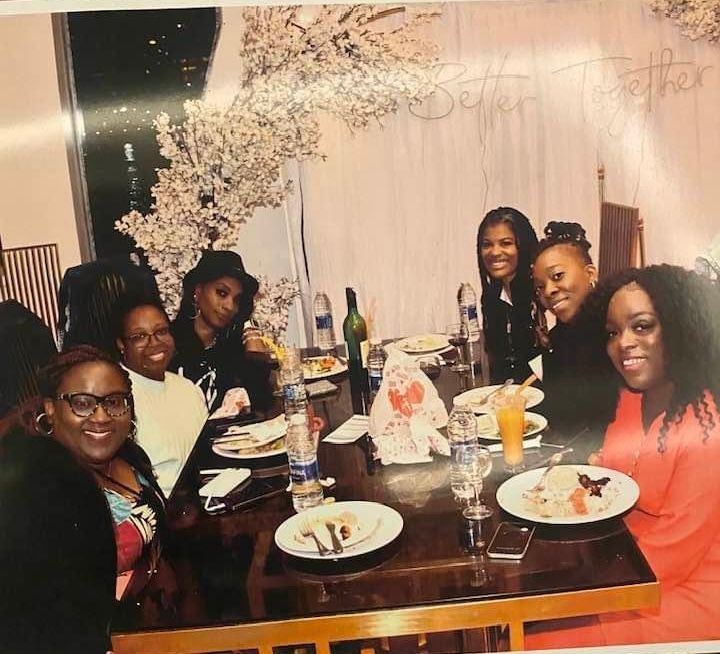A group of women are sitting at a table with plates of food.