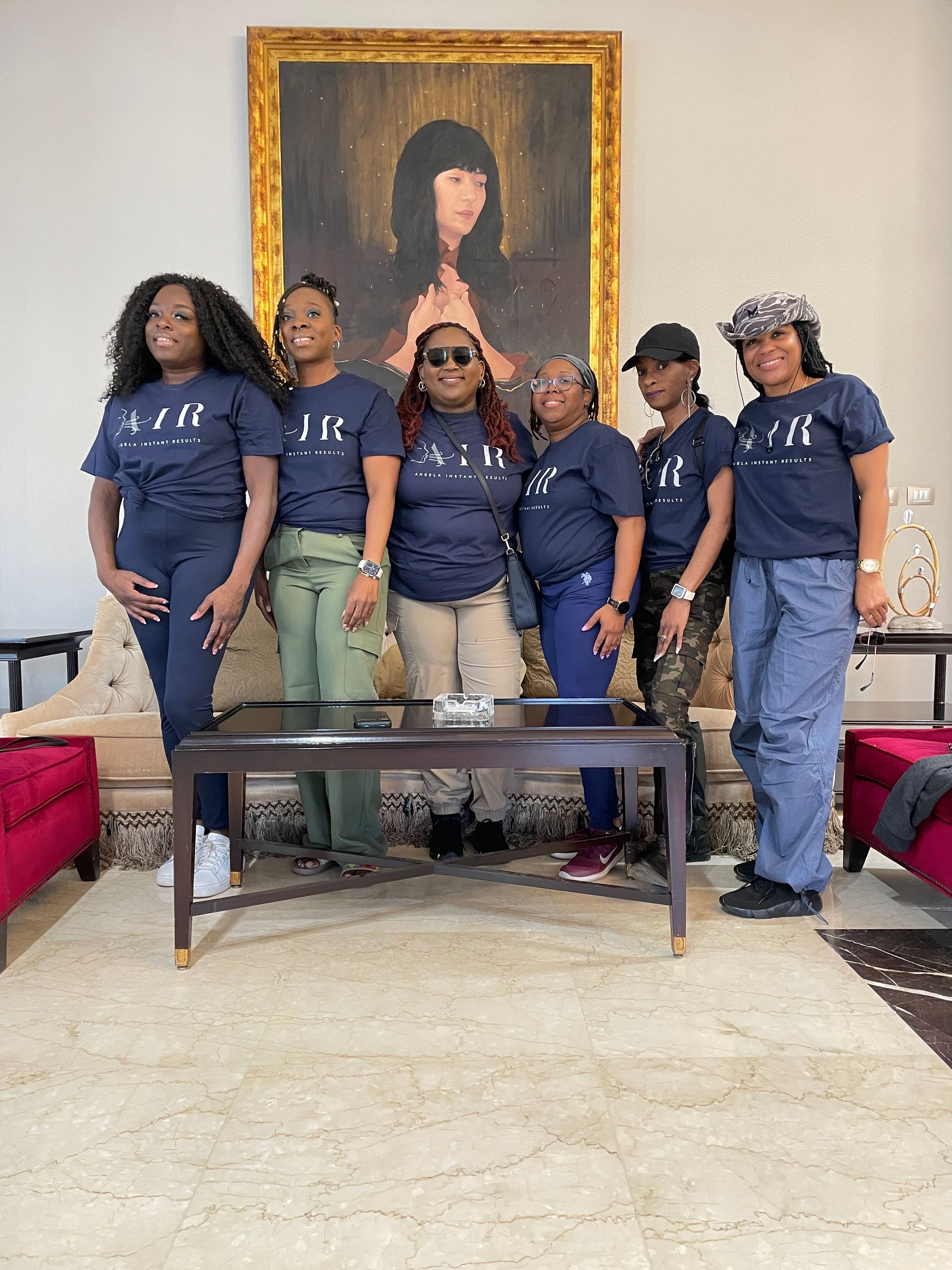 A group of women are posing for a picture in front of a painting.