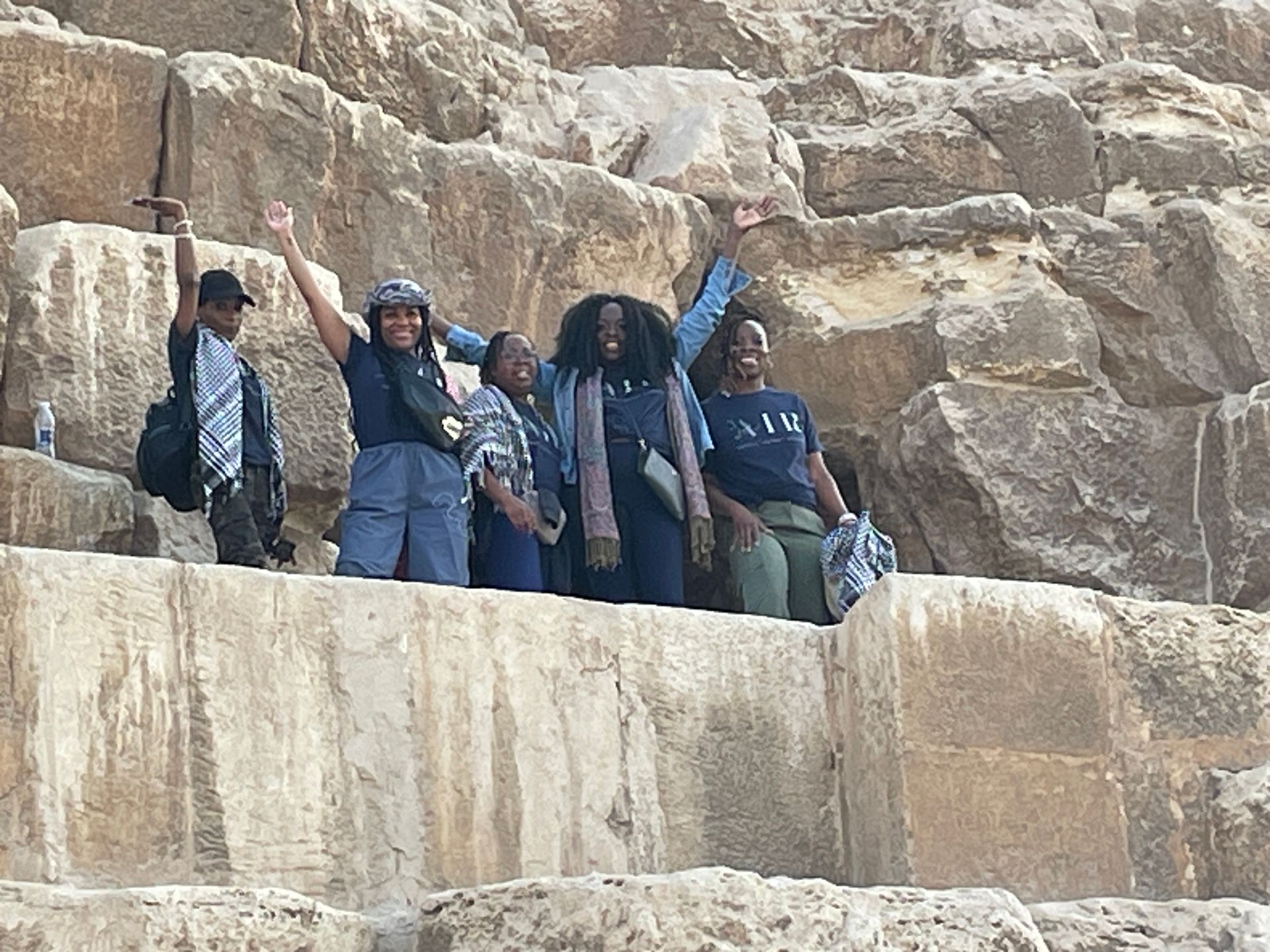 A group of people are standing on top of a large rock.