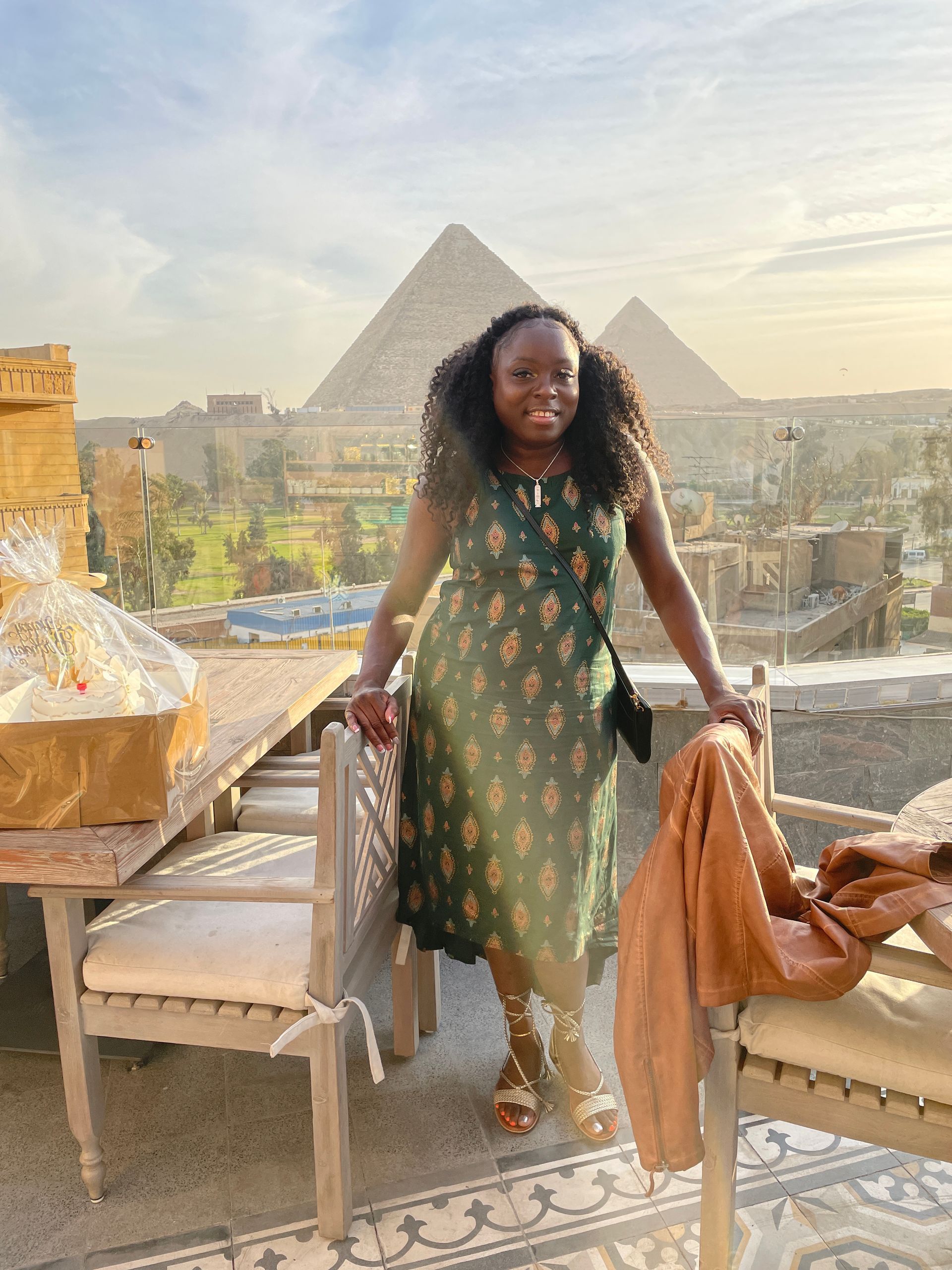 A woman in a green dress is standing in front of two pyramids.