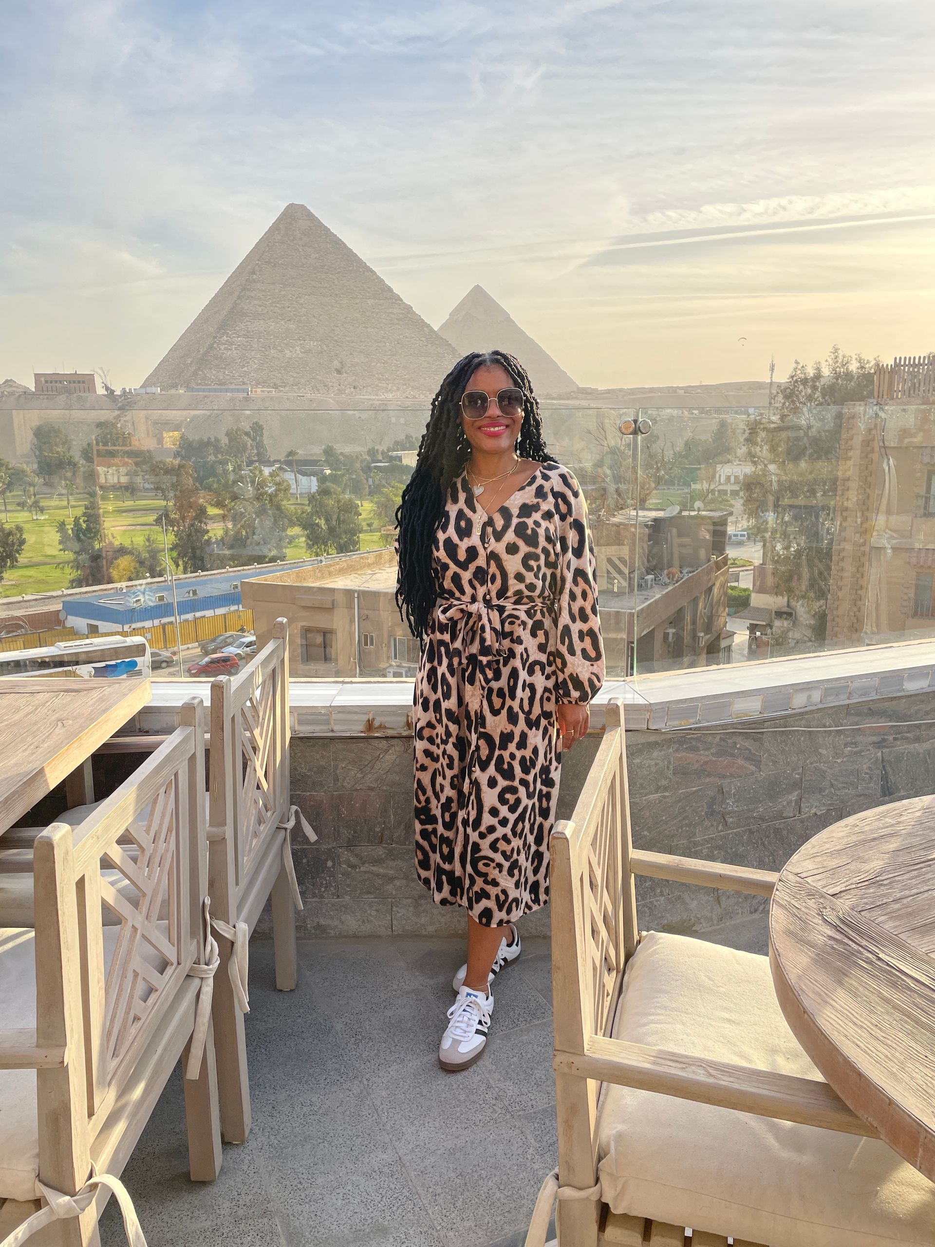 A woman in a leopard print dress is standing in front of two pyramids.