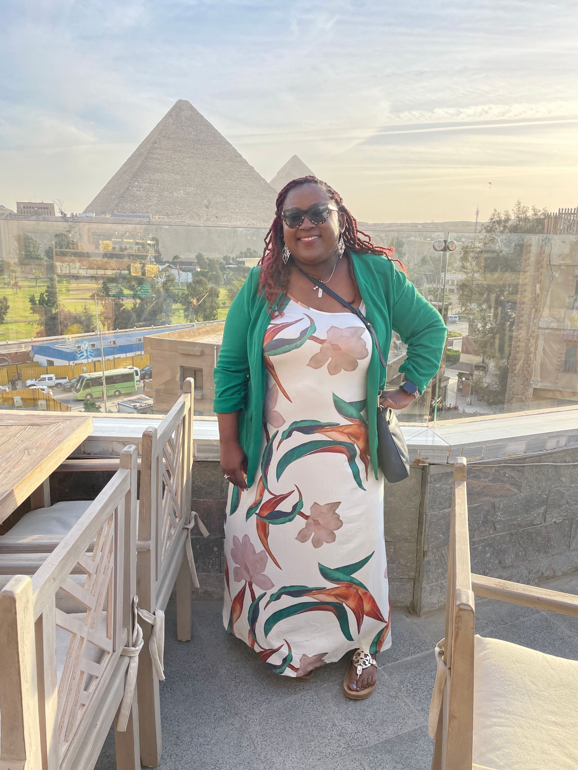 A woman in a dress is standing in front of a pyramid.