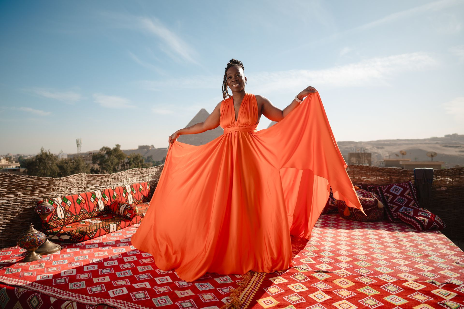 A woman in an orange dress is standing on a red rug.