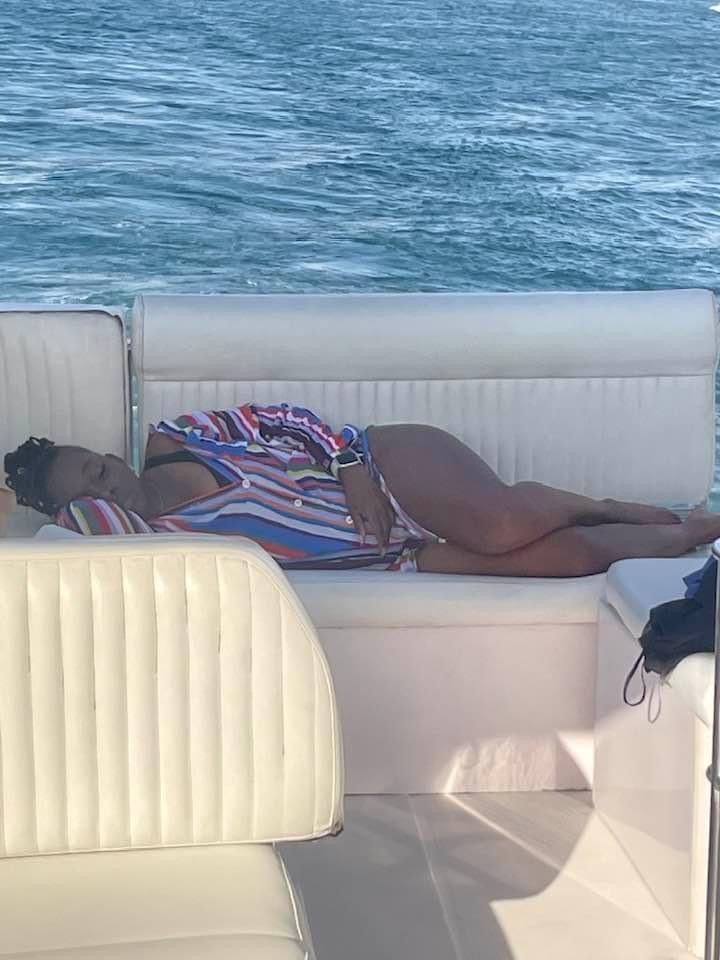 A woman is laying on a boat in the water.