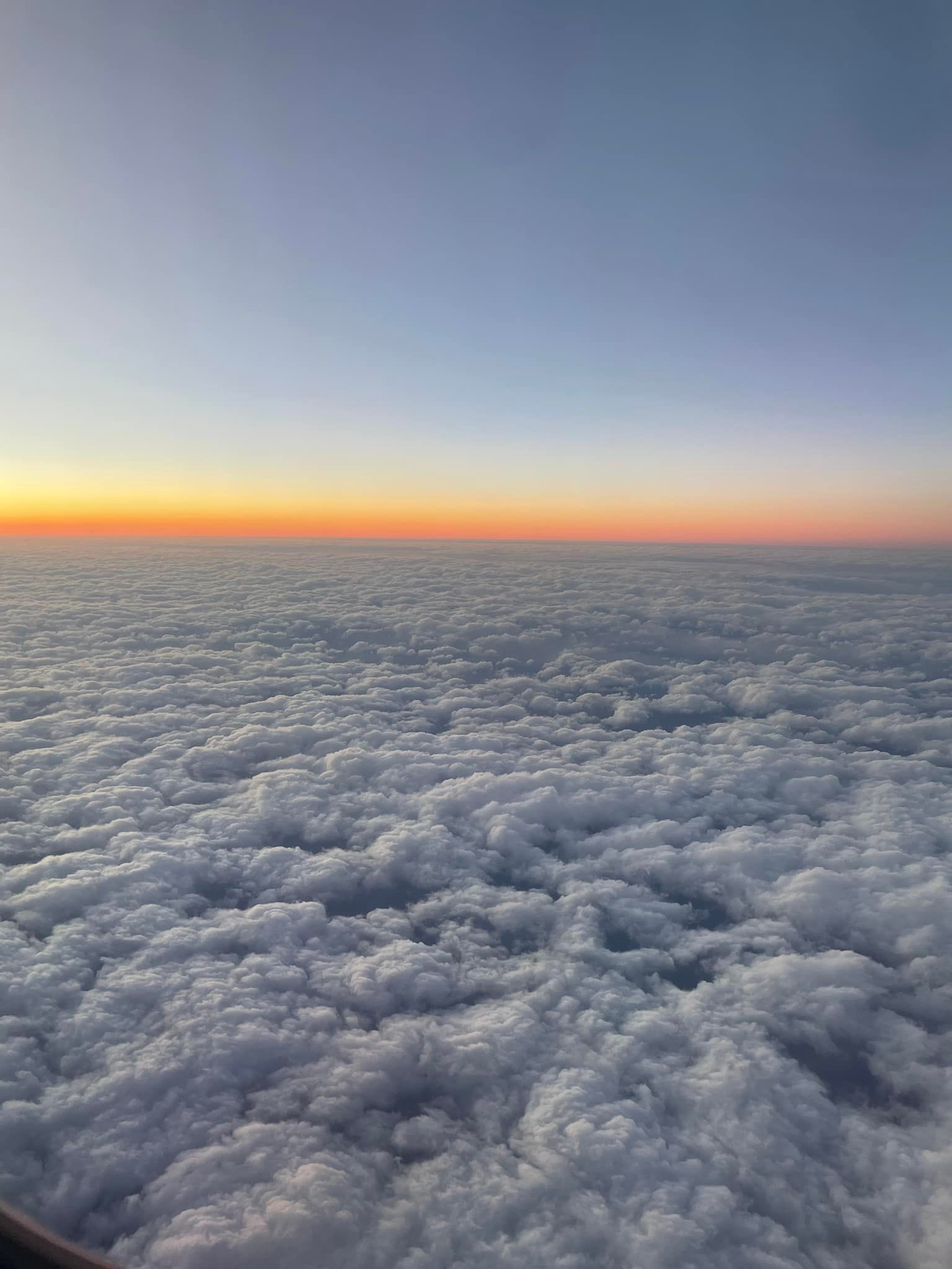 A view of the clouds from an airplane window at sunset.