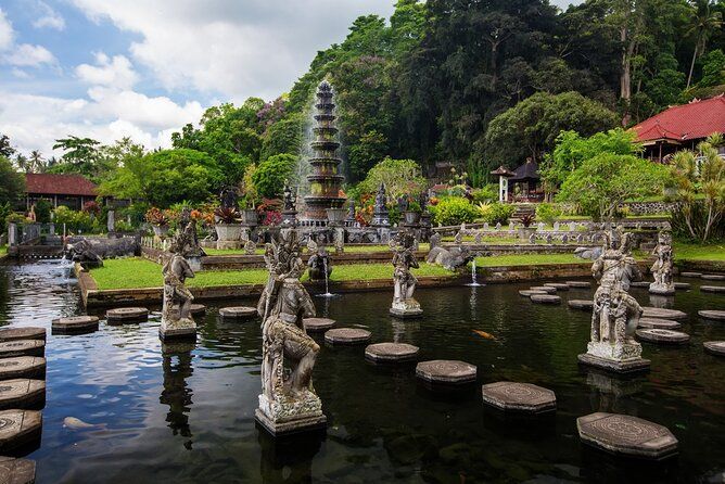 A pond filled with statues and a fountain in a park.