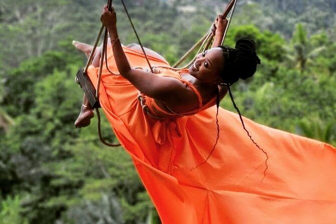 A woman in an orange dress is flying through the air on a swing.