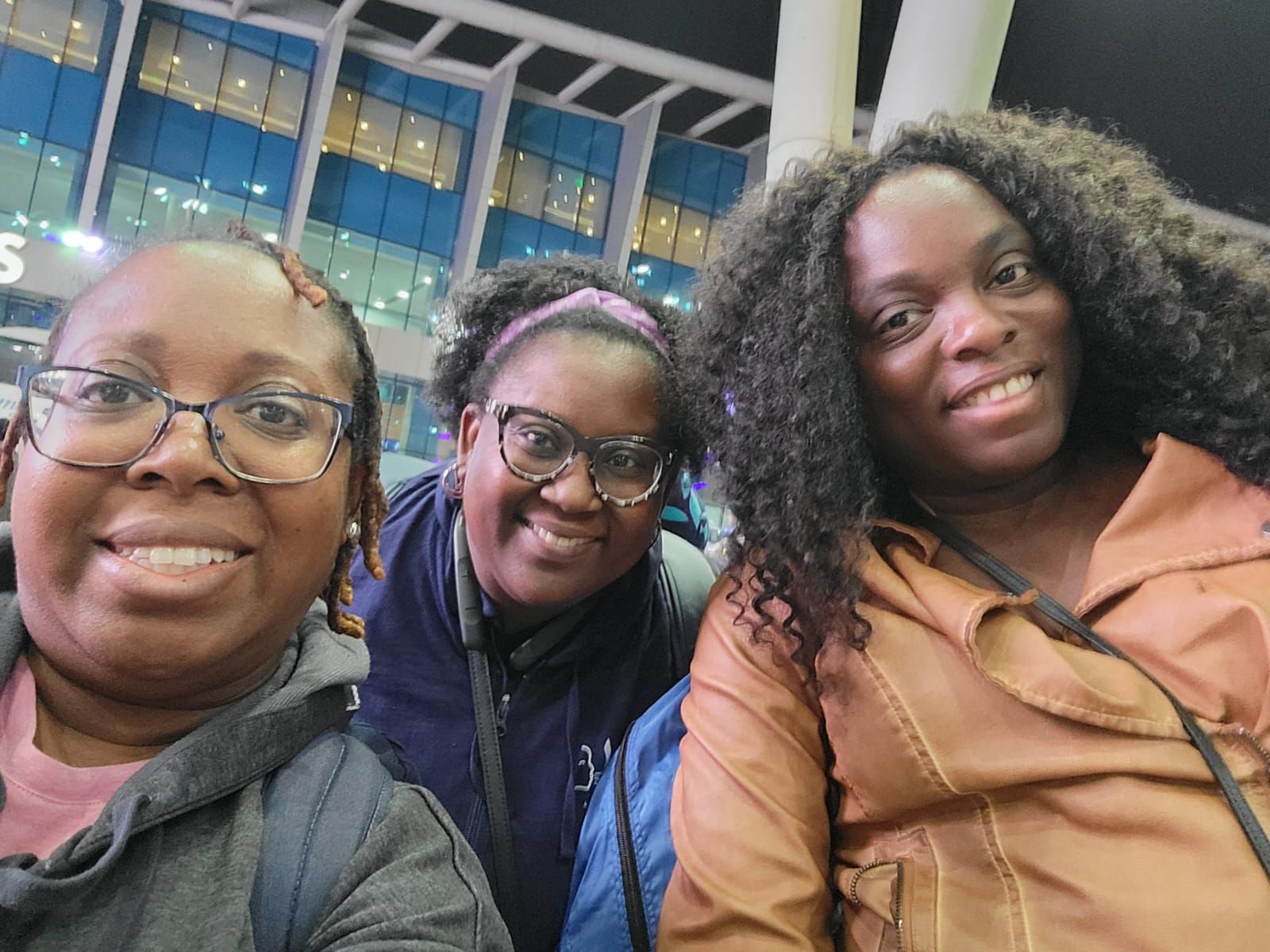 Three women are posing for a picture together in front of a building.