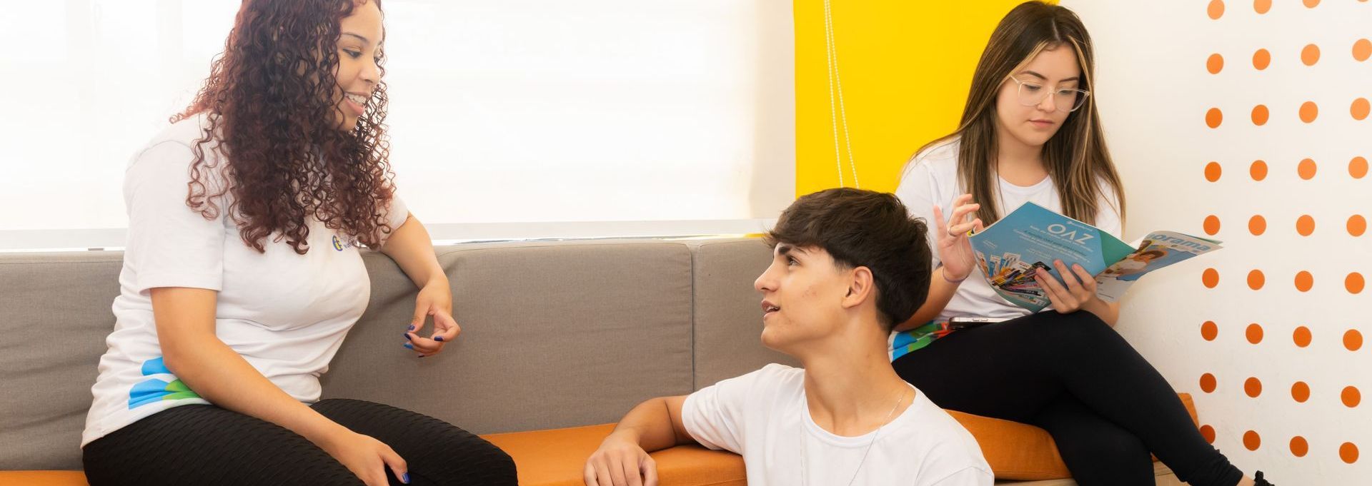 Um grupo de jovens está sentado em um sofá conversando entre si.