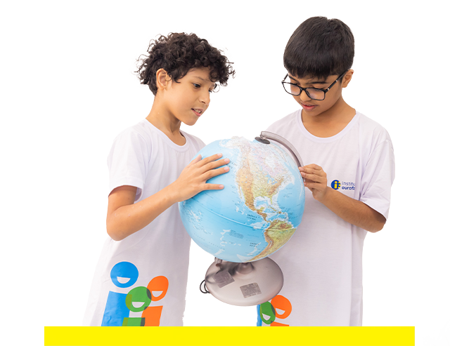 Dois meninos estão olhando juntos para um globo.