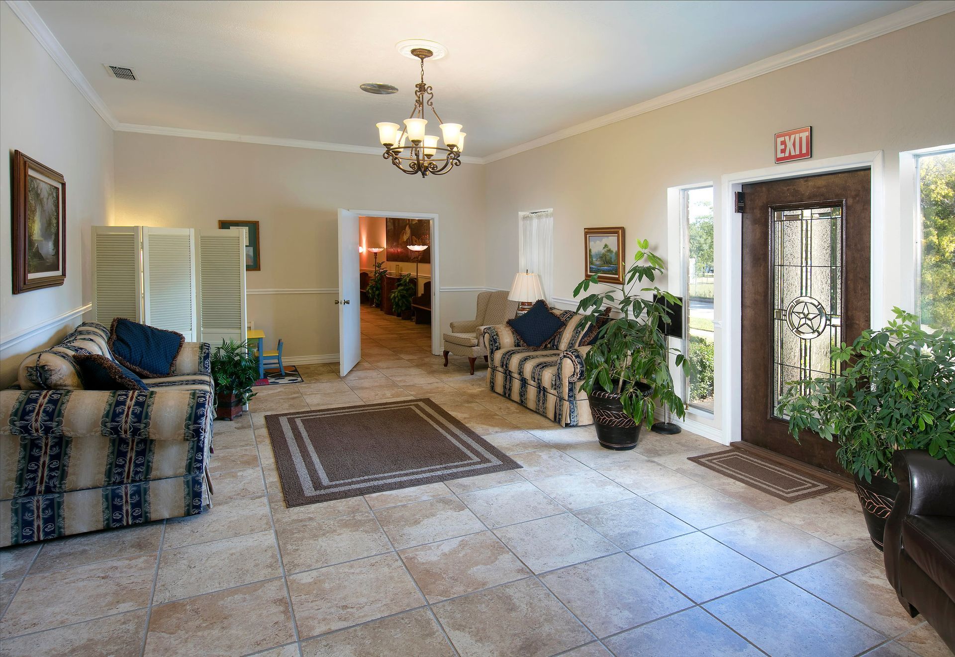 A living room with a couch and chairs and an exit sign