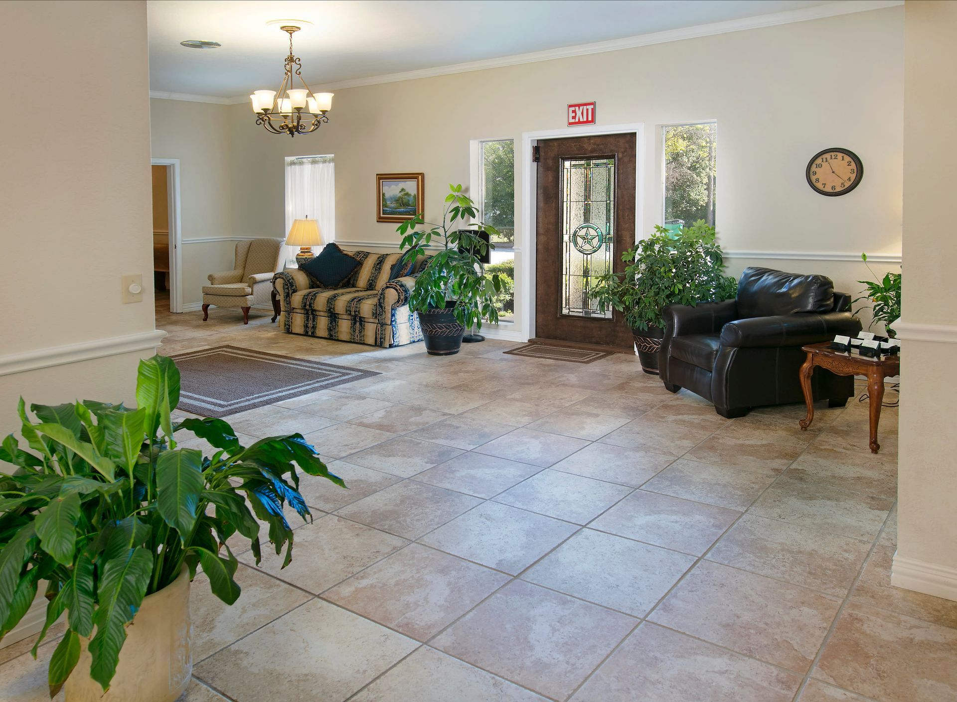 A living room with a couch and chairs and a clock on the wall