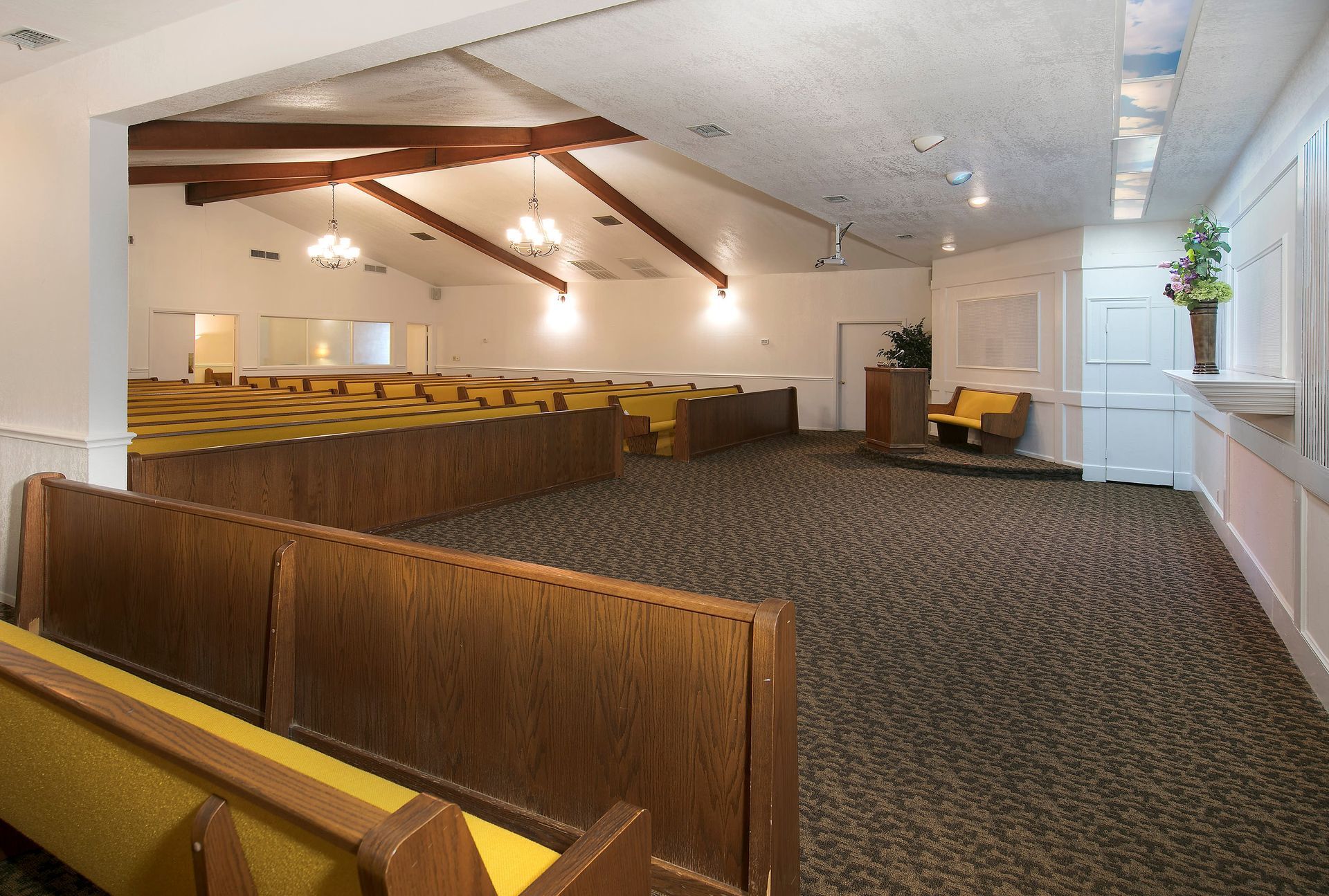 An empty church with wooden benches and yellow seats
