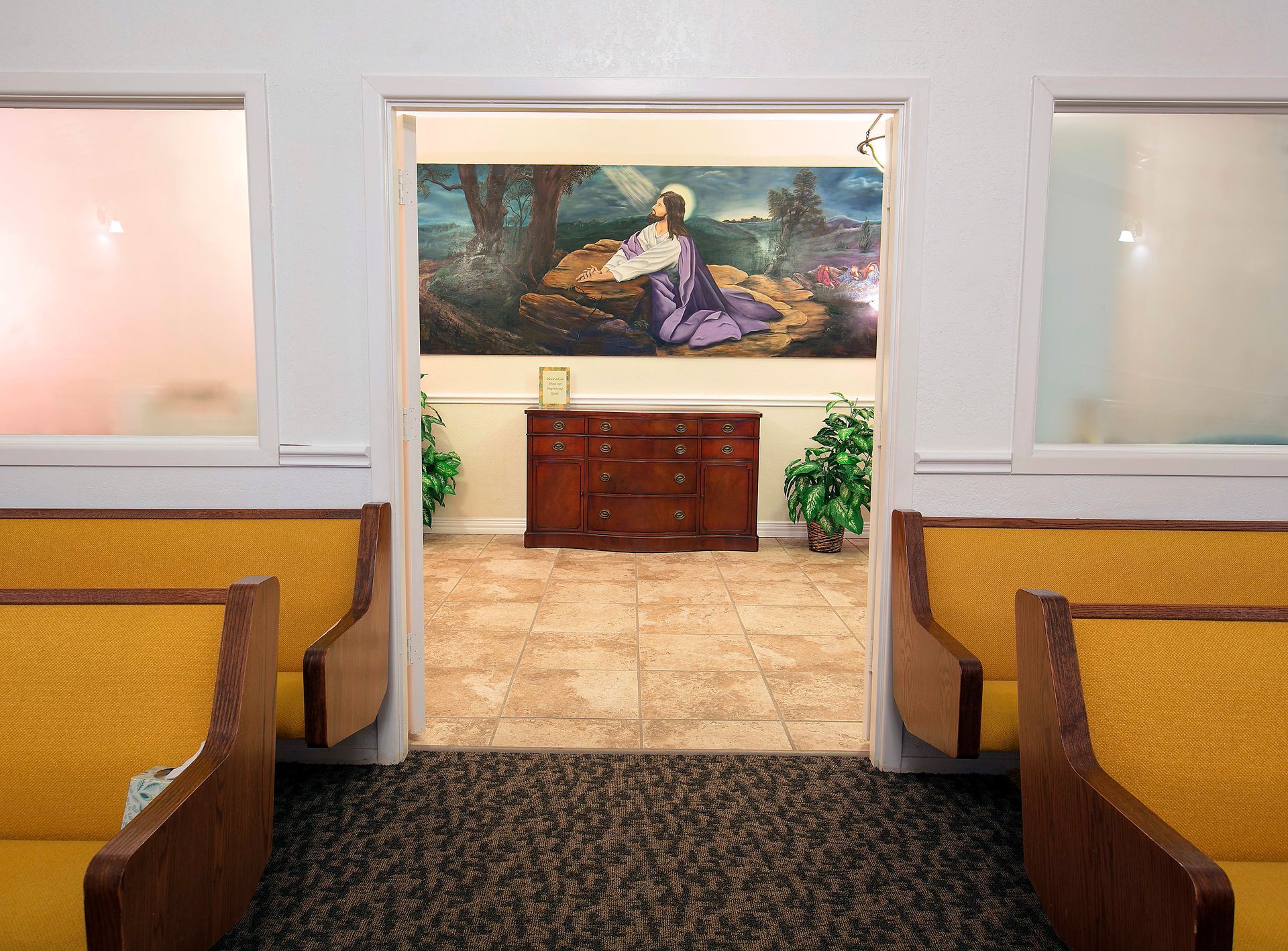 A church waiting room with a painting of jesus on the wall.