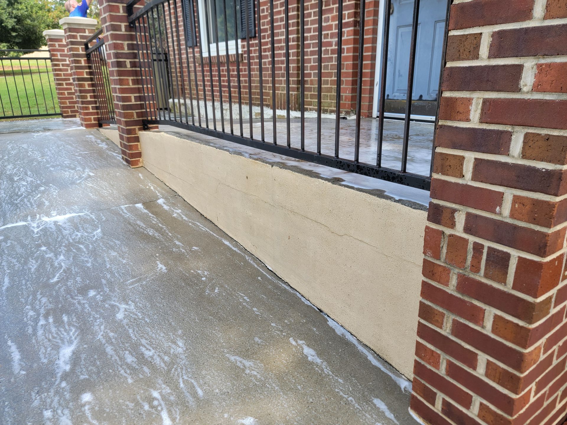 Brick and stucco house exterior with a concrete walkway and black railing.