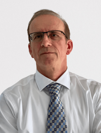 A man wearing glasses and a tie is looking at the camera.