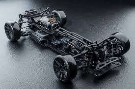 Black RC car chassis with visible components on a dark reflective surface.