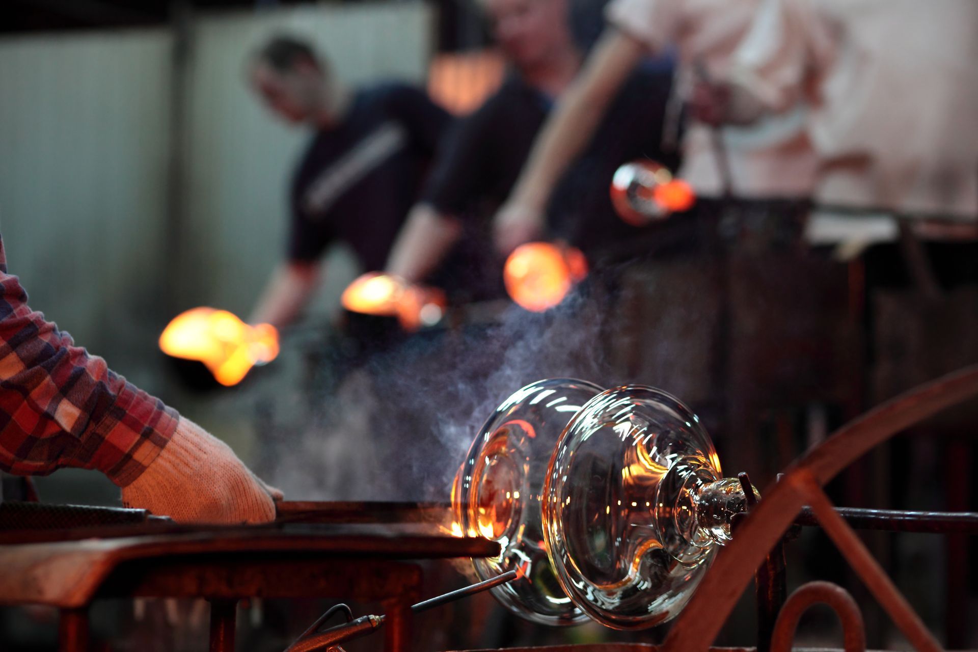 A man is blowing glass with a torch in a workshop.