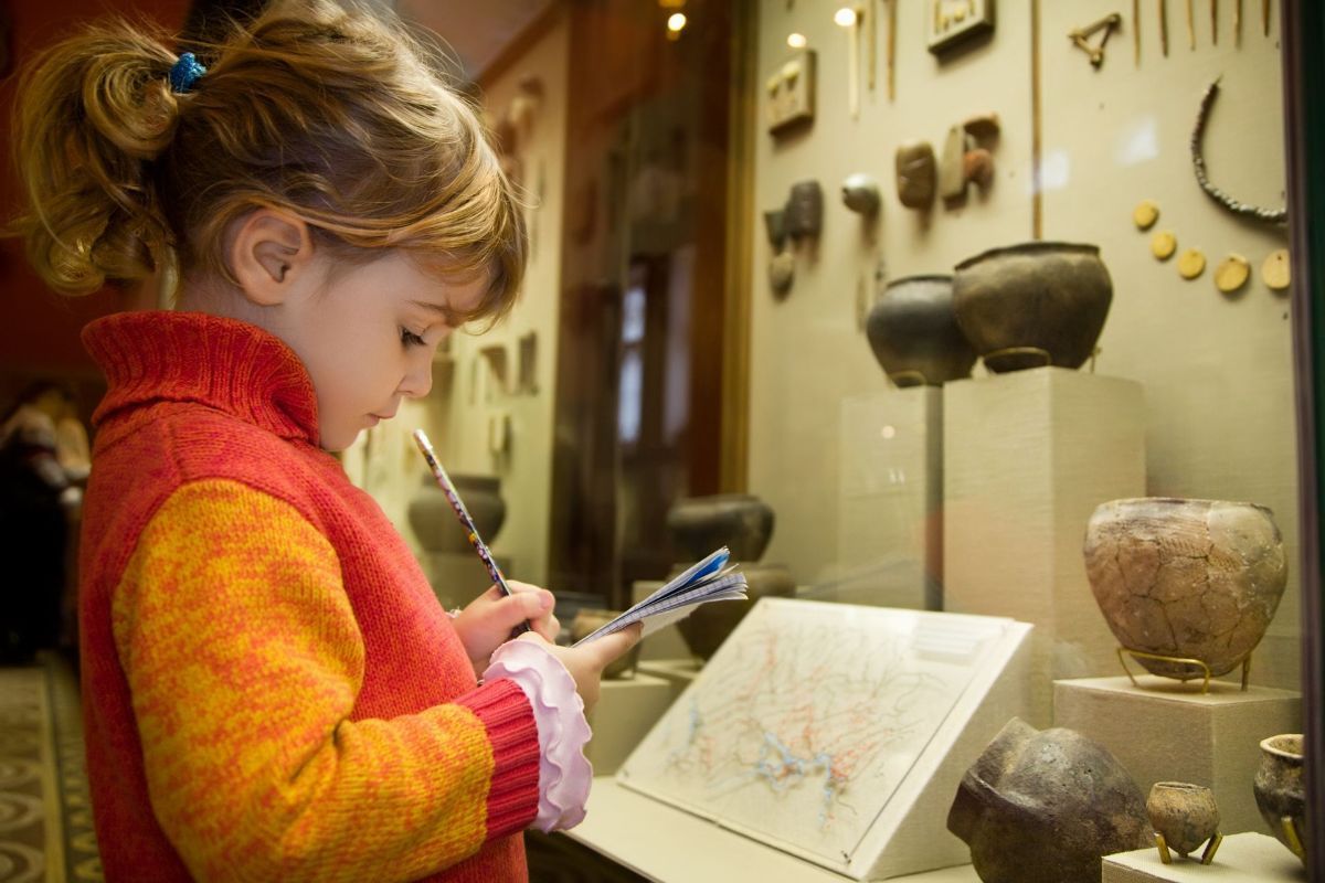 A little girl is looking at a map in a museum.