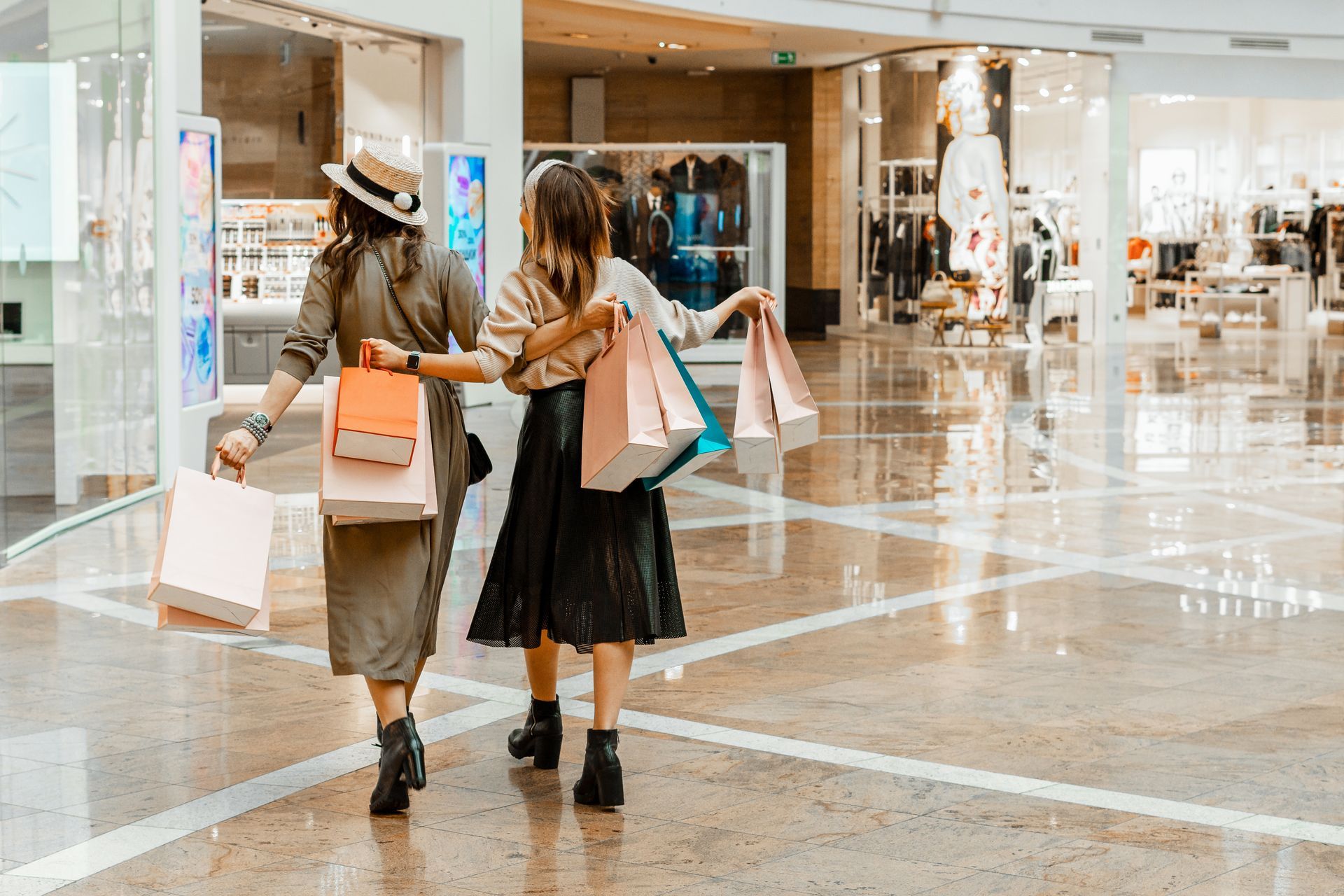 Two women are walking through a shopping mall holding shopping bags.