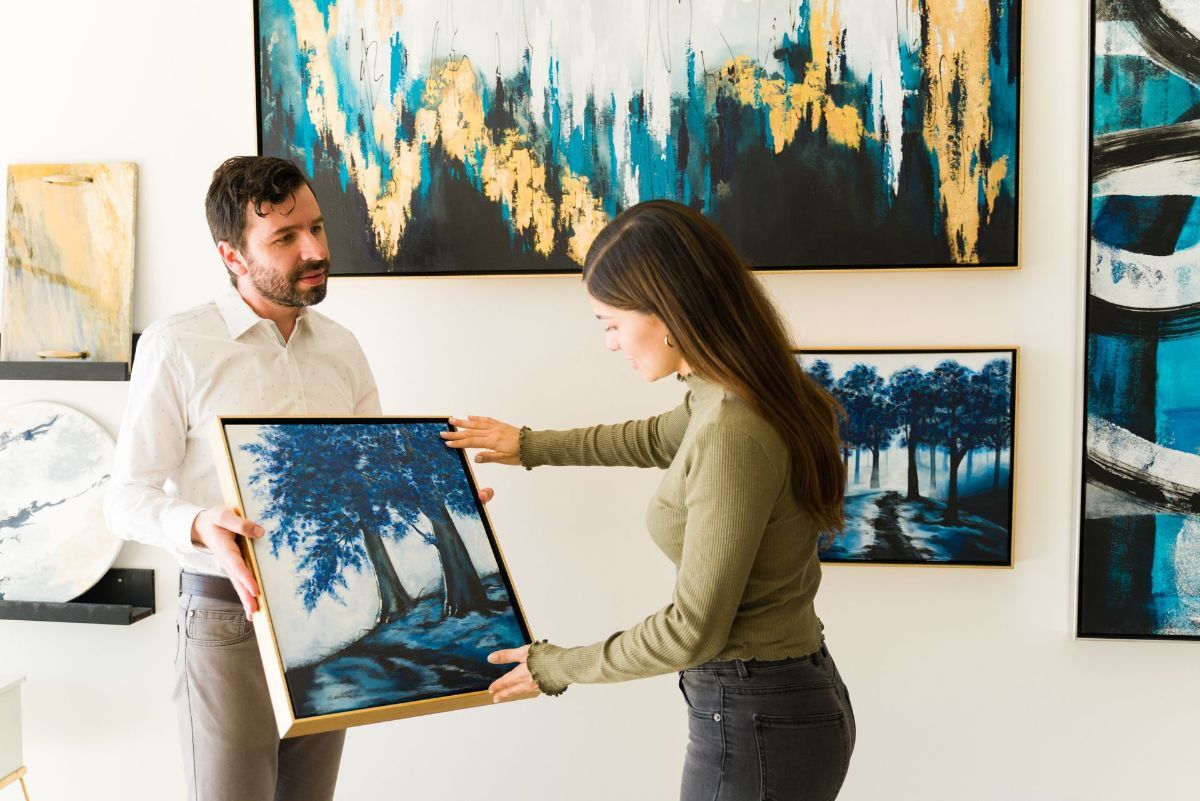 A man and a woman are looking at a painting in a gallery.