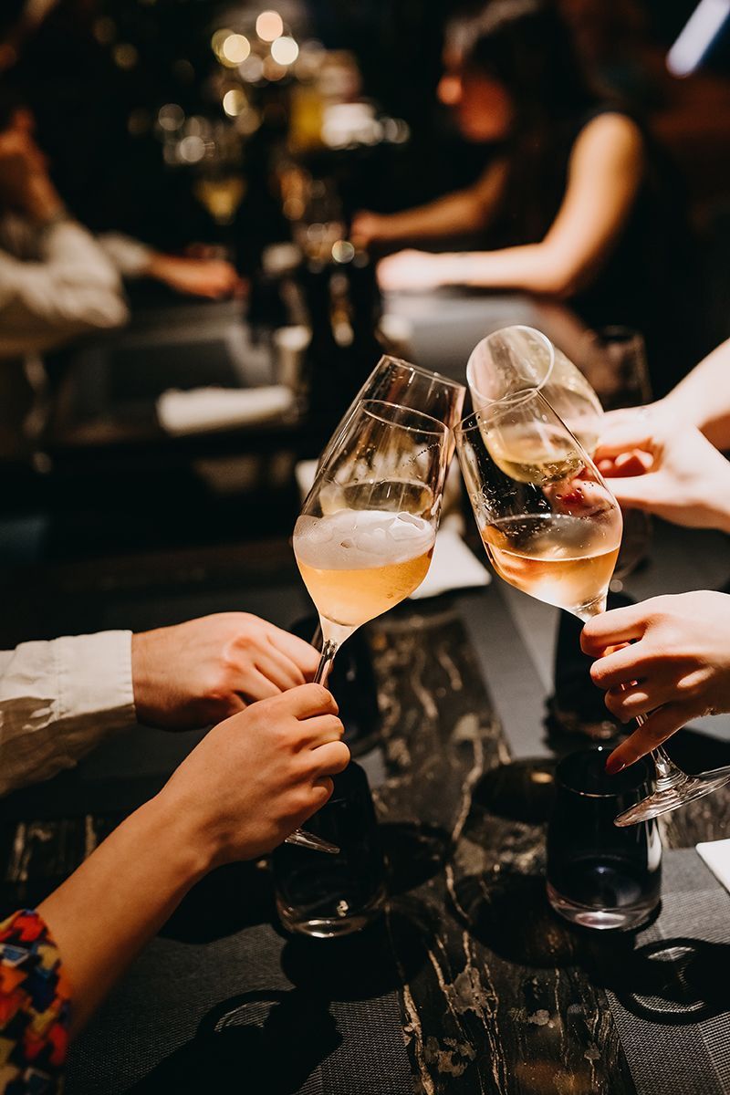 A group of people are toasting with wine glasses at a table.